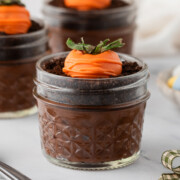 Easter Dirt Cups on a table with a carrot made of starwberries on top.