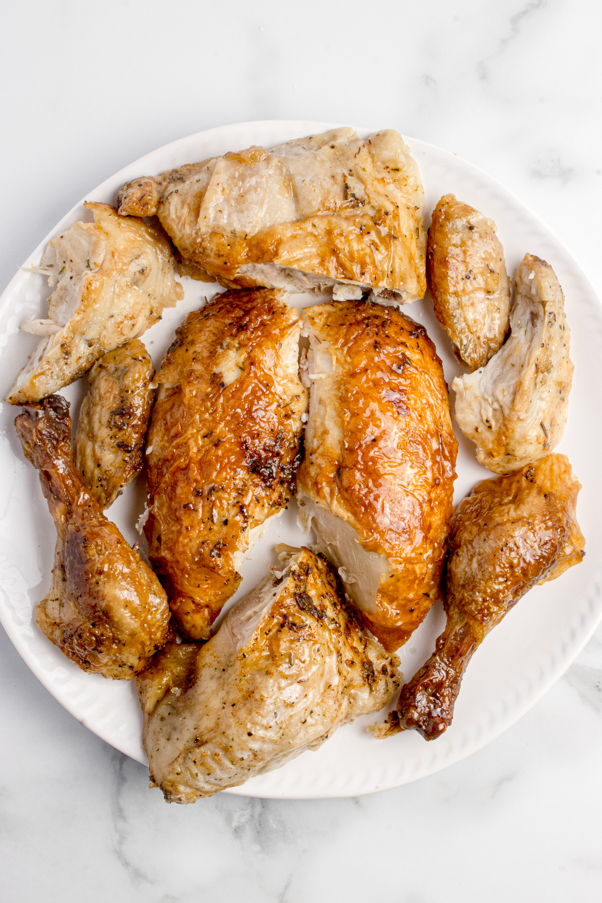 All of the carved parts of a rotisserie chicken on a plate.