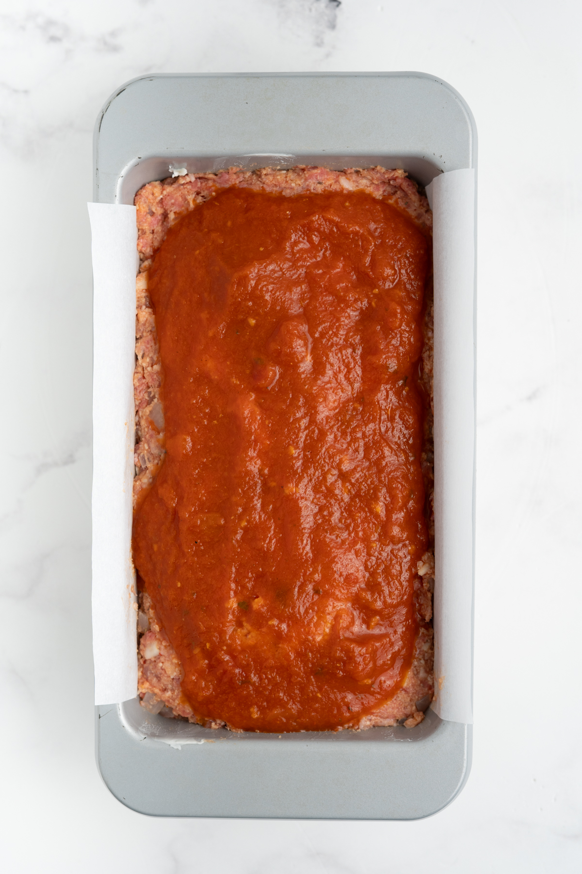 The marinara sauce spread on top of the meatloaf.