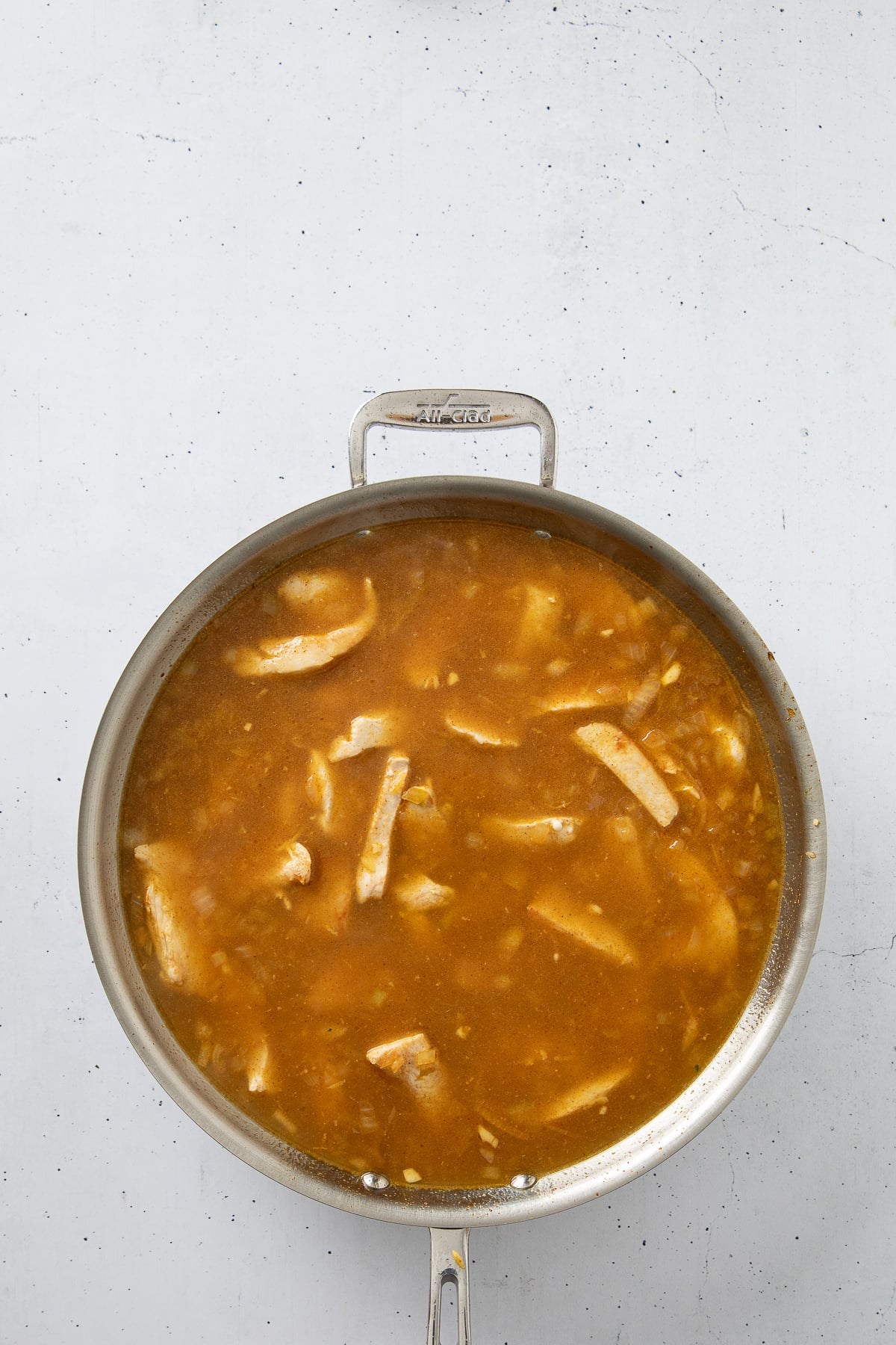 Broth and lemon added and simmering in a pot.