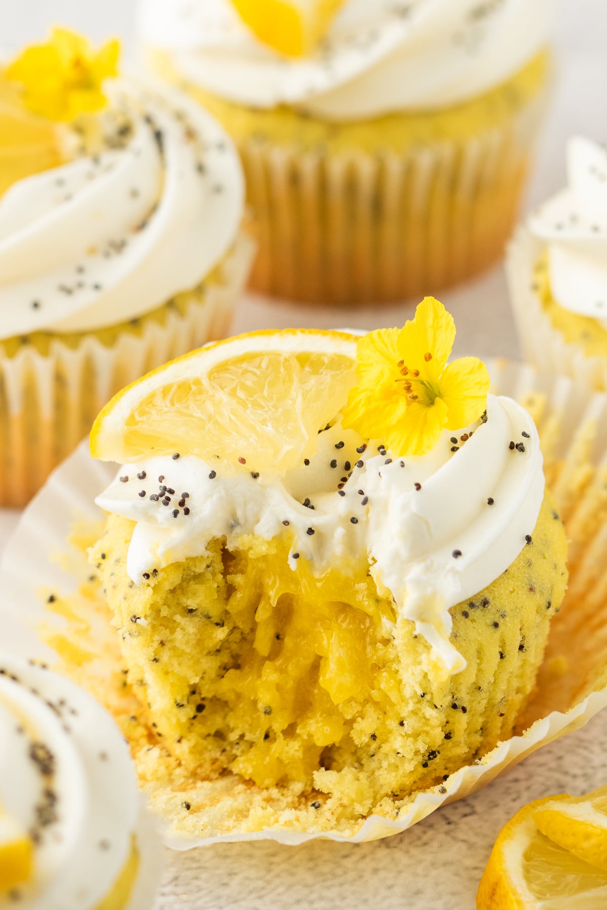 A lemon cupcake with a bite taken out of it on a cupcake liner.