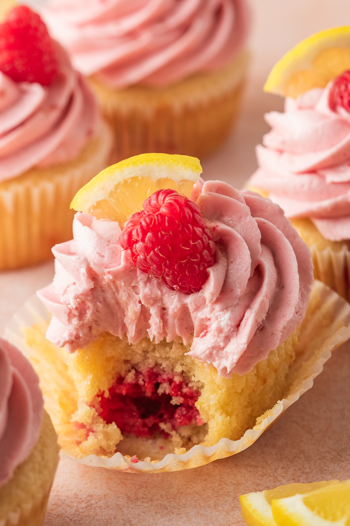 A raspberry cupcake with a bite taken out of it.