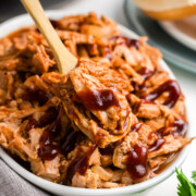 Slow cooker pulled pork tenderloin being scooped out.