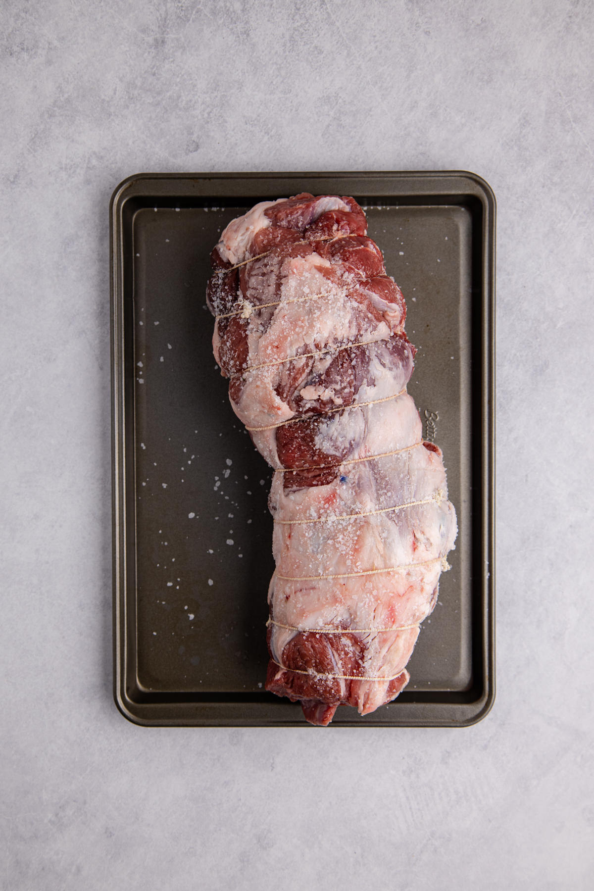 Leg of lamb, rolled, tied, and seasoned.