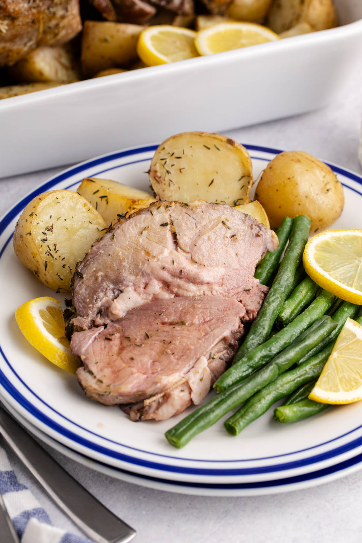 A slice of boneless lamb leg with a side of potatoes and green beans.