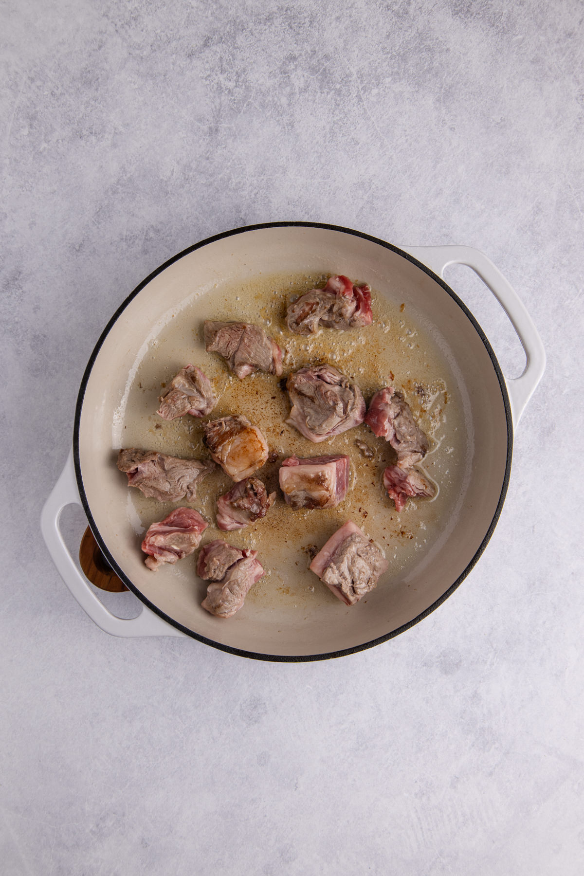 Lamb chunks in a skillet browning.