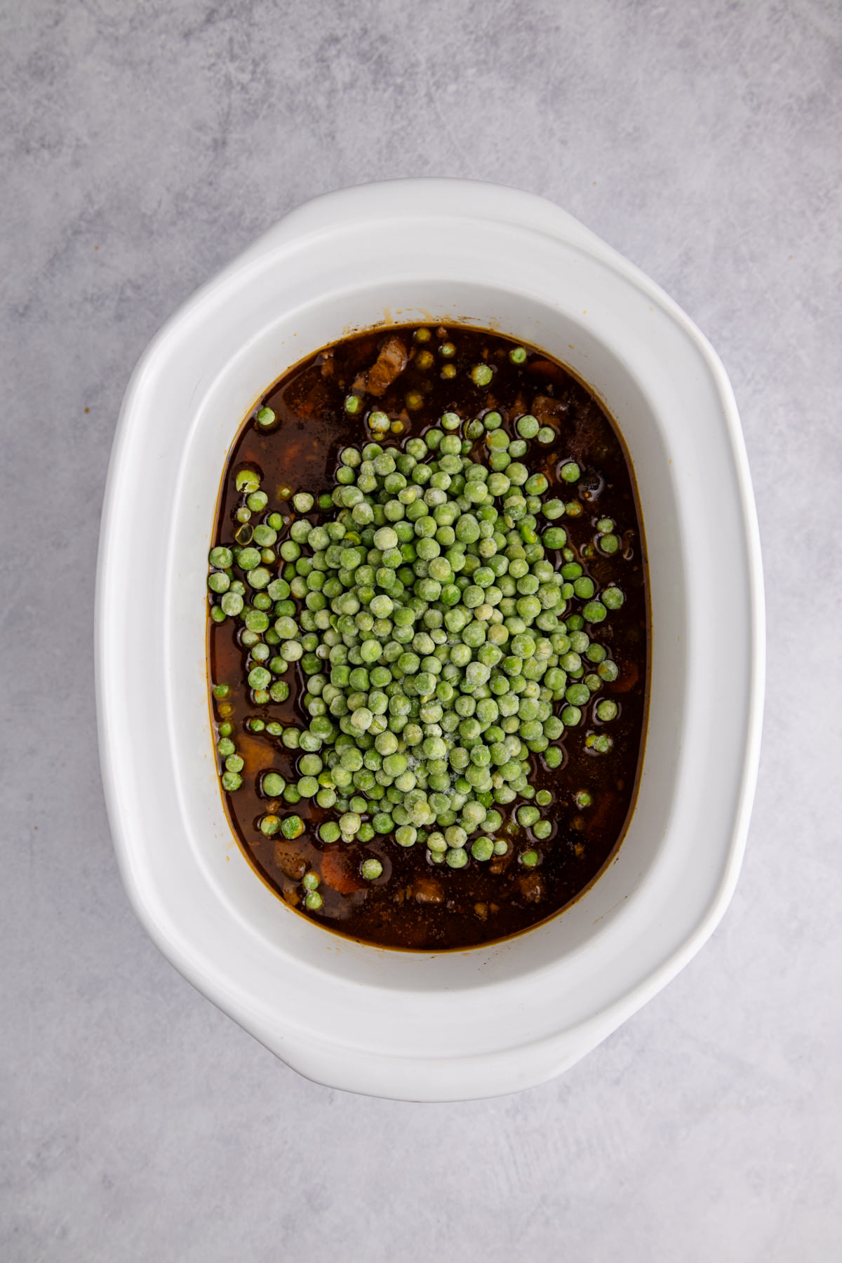 Flour and water mixture added to the ingredients, and peas added on top.