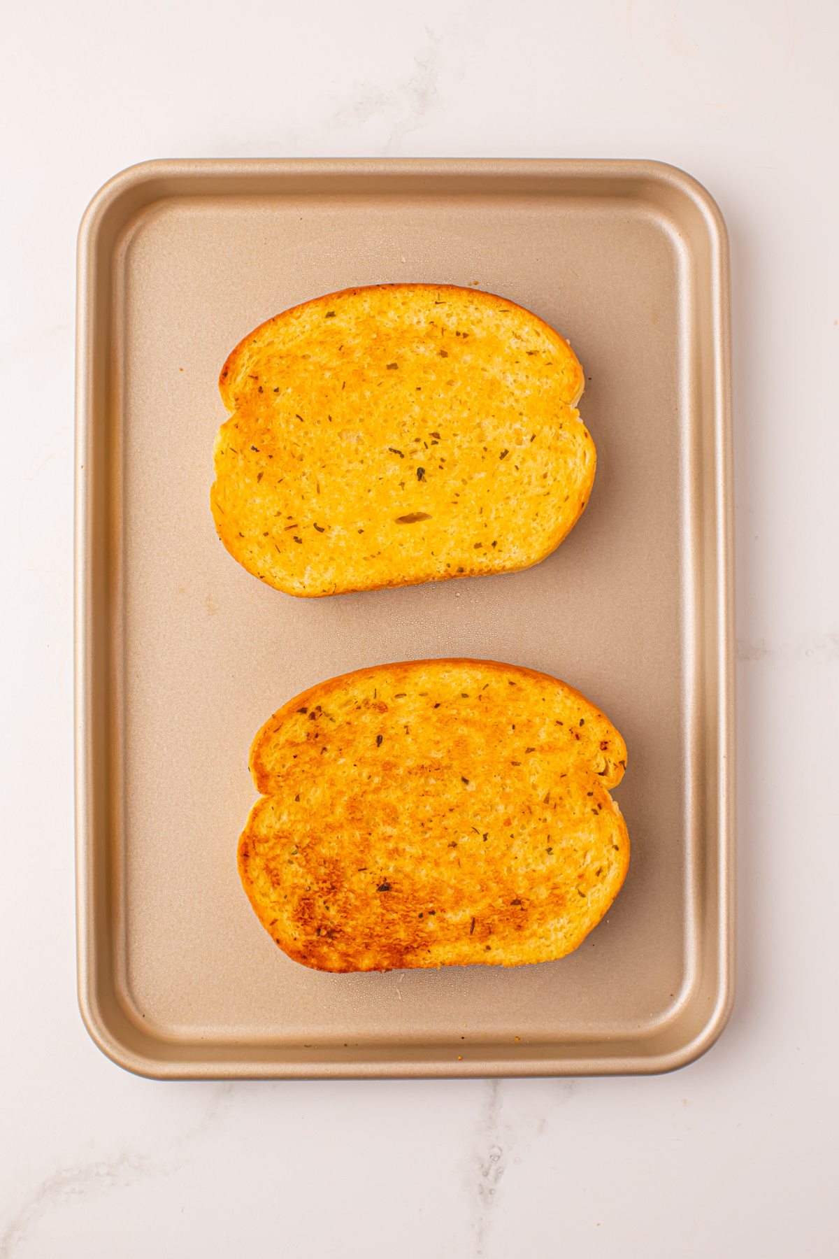 Lightly golden Texas Toast on a rimmed baking sheet.