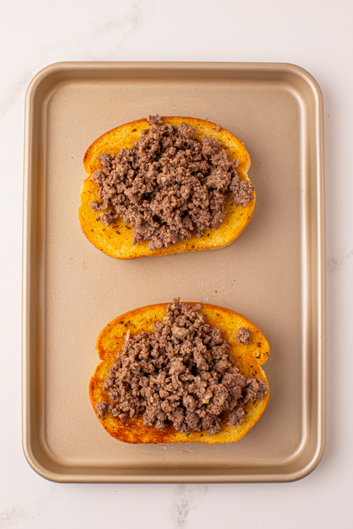 Cooked ground beef added to top of Texas toast.