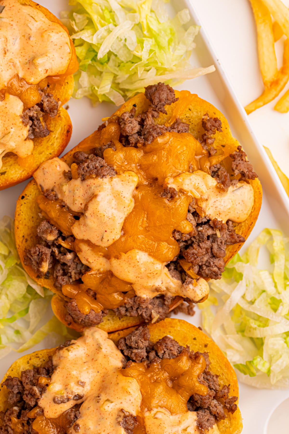An open-faced Texas Toast Big Mac on a platter with shredded lettuce.