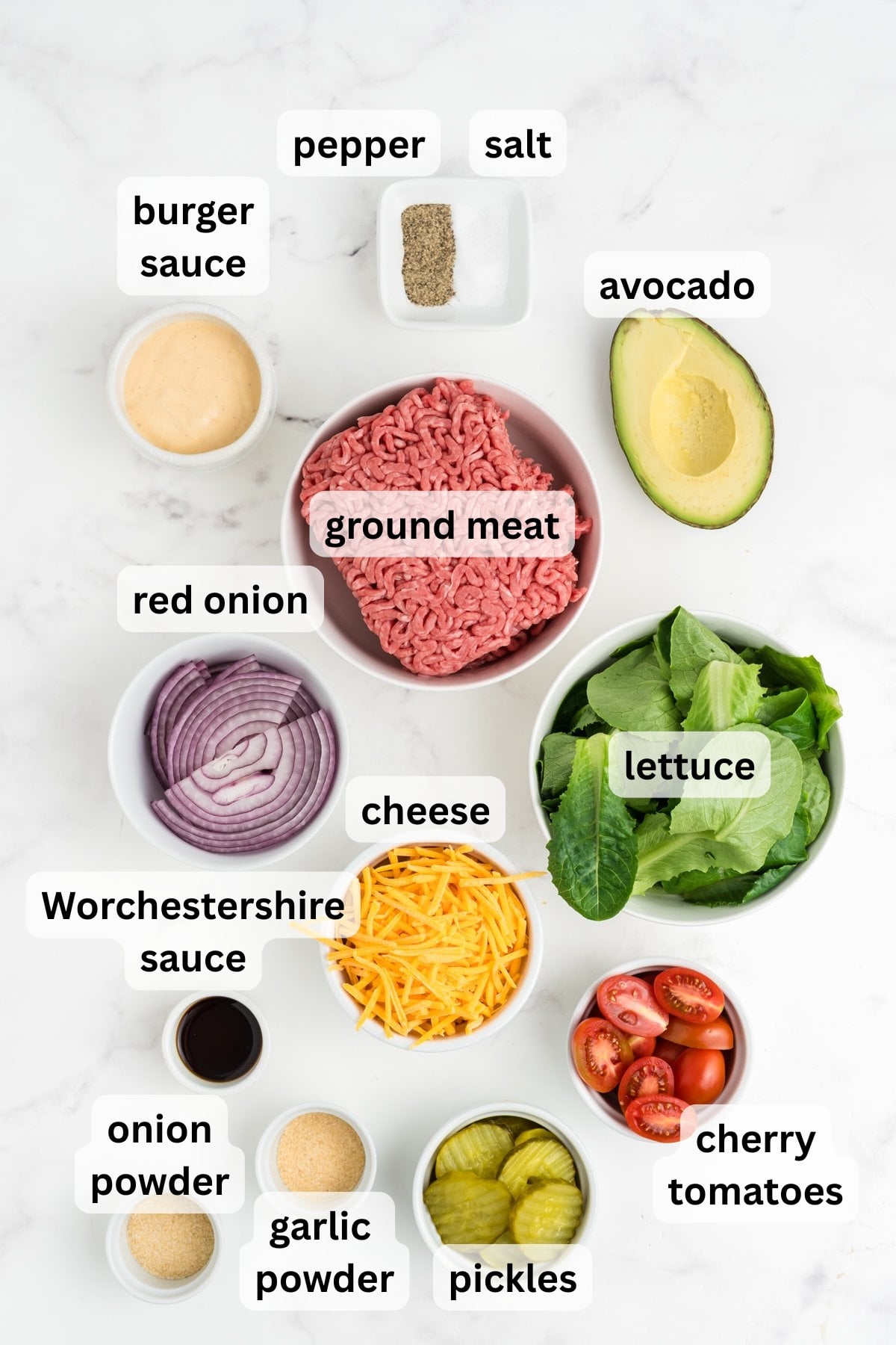 All of the ingredients needed to make burger bowls in bowls on a counter.