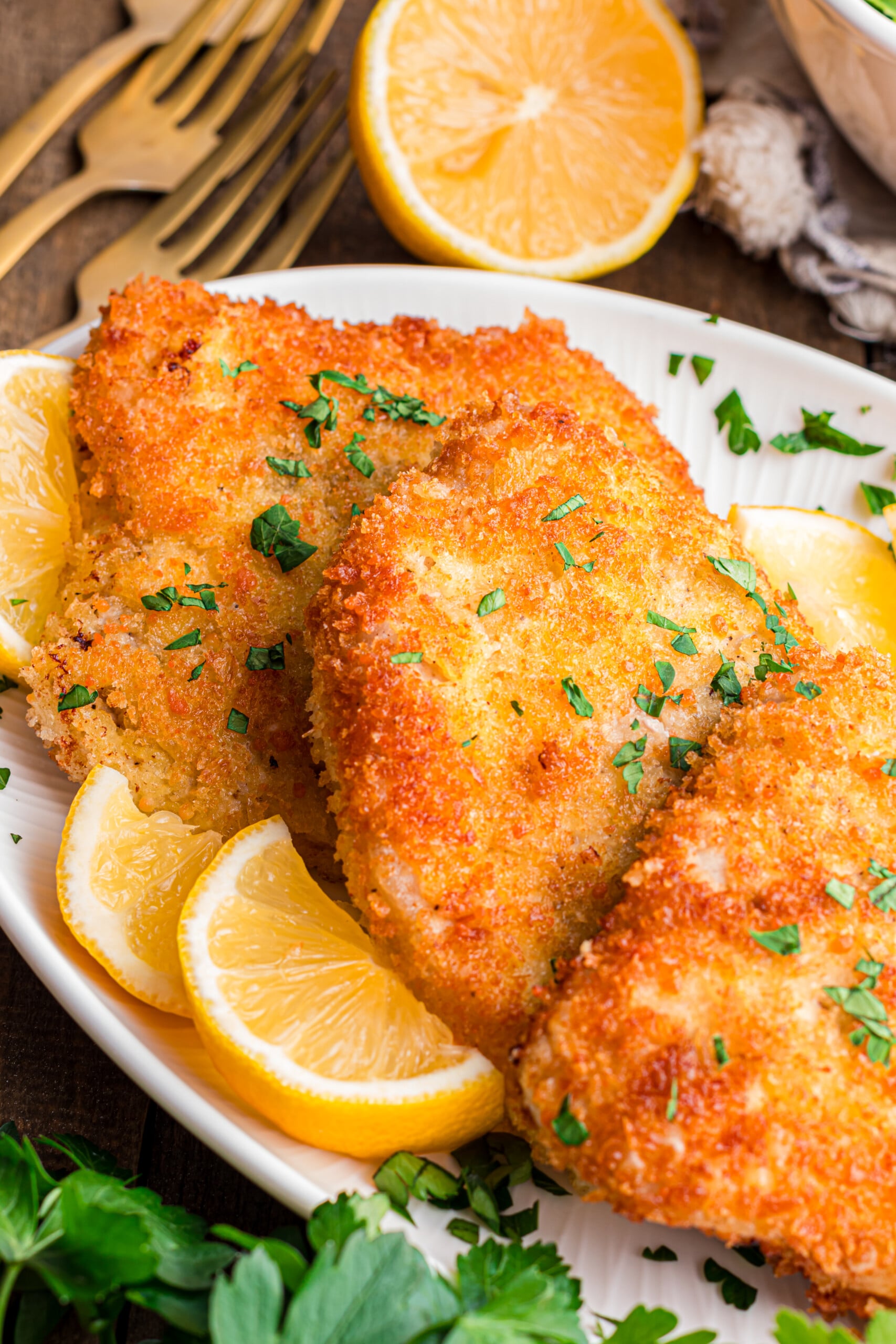 A plate filled with breaded pork garnished with lemon slices. 