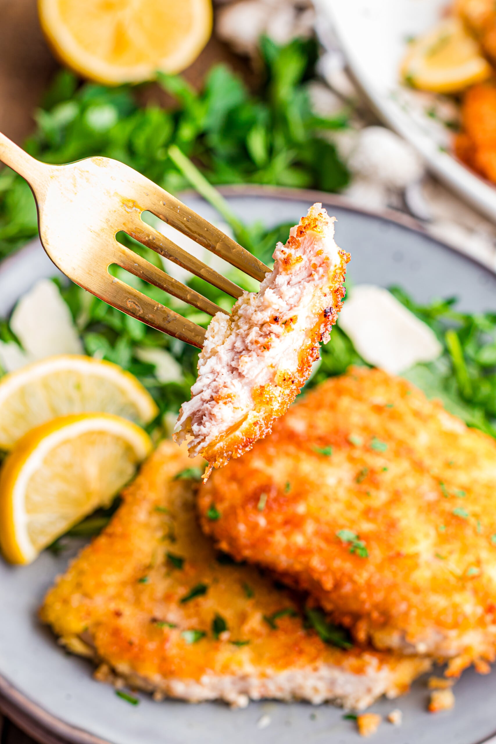 A piece of pork cutlet Milanese on a fork.