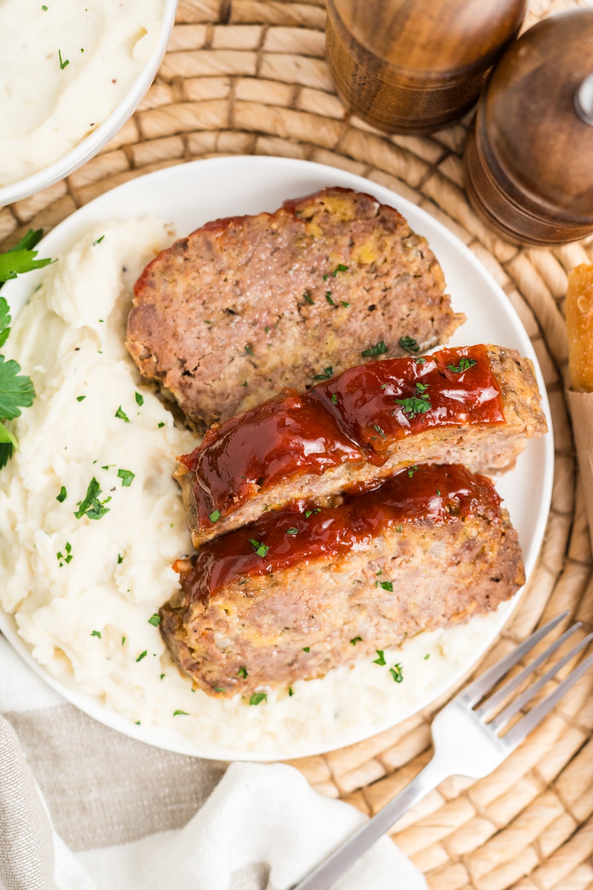A plate with slices of meatloaf with a side of mashed potatoes.