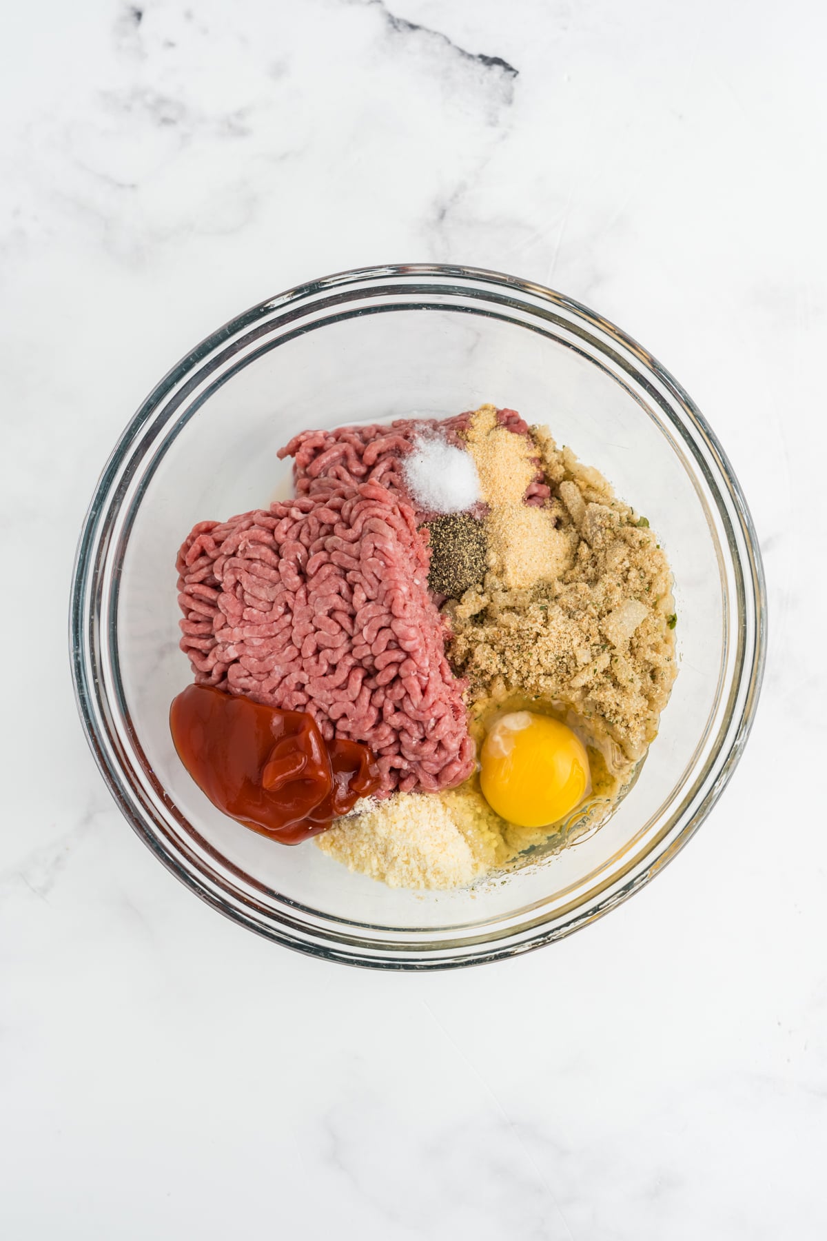 All the ingredients for the meatloaf in a mixing bowl.