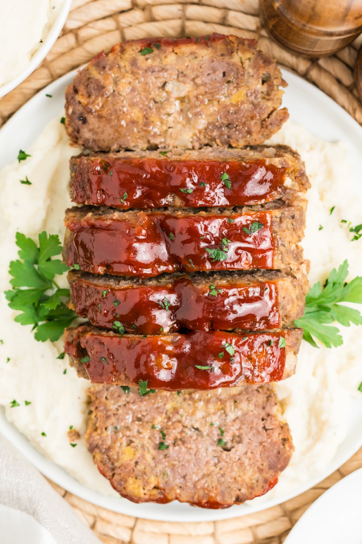 A 1 pound meatloaf sliced over potatoes.