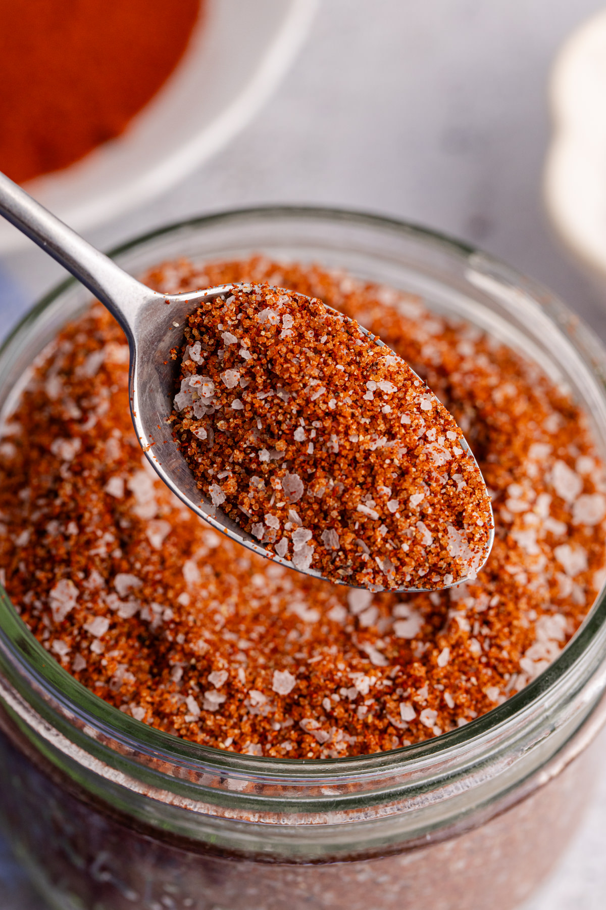 A spoon holding up some spice rub for brisket. 