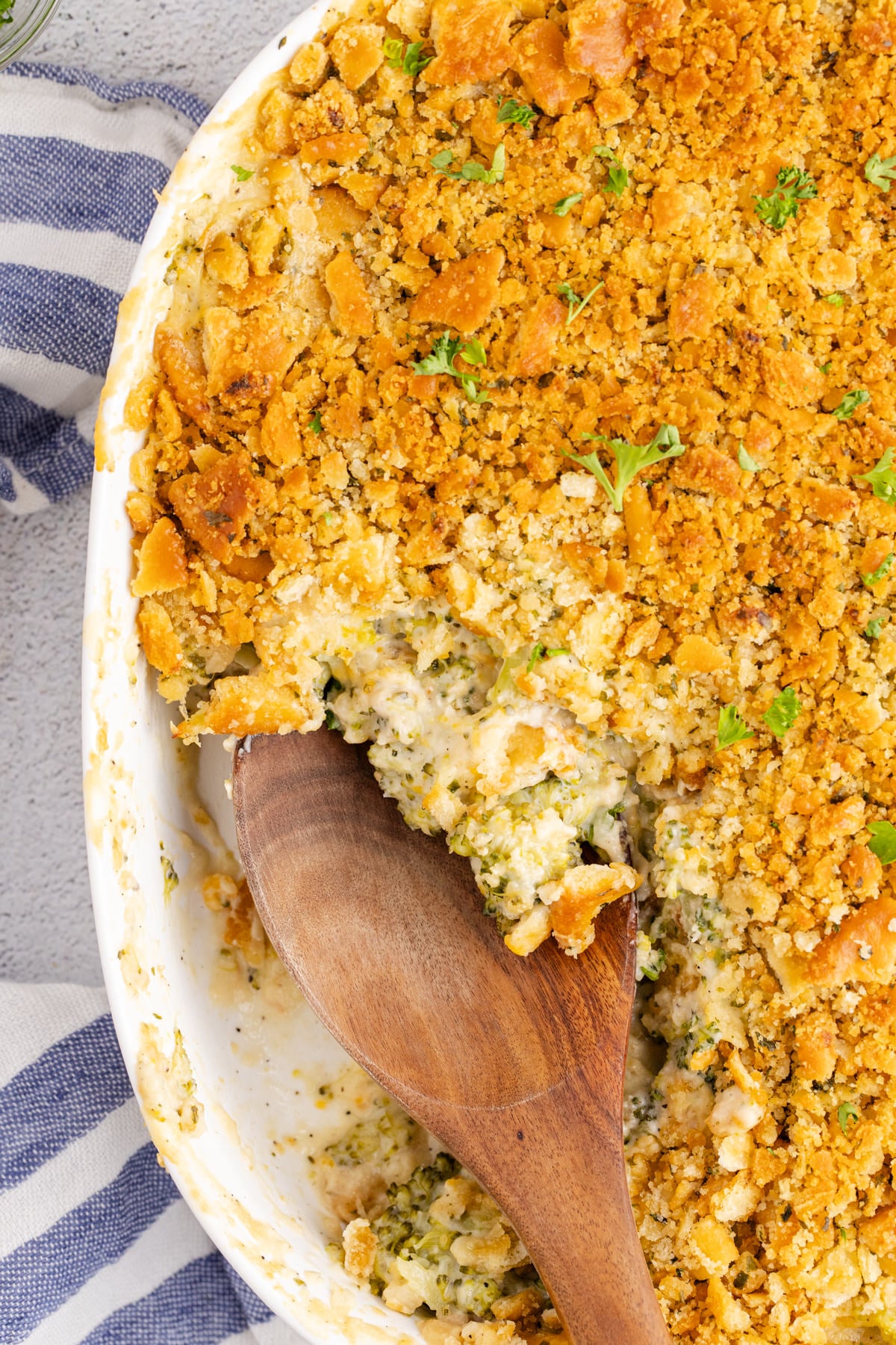 Broccoli casserole being scooped up with a wooden spoon.