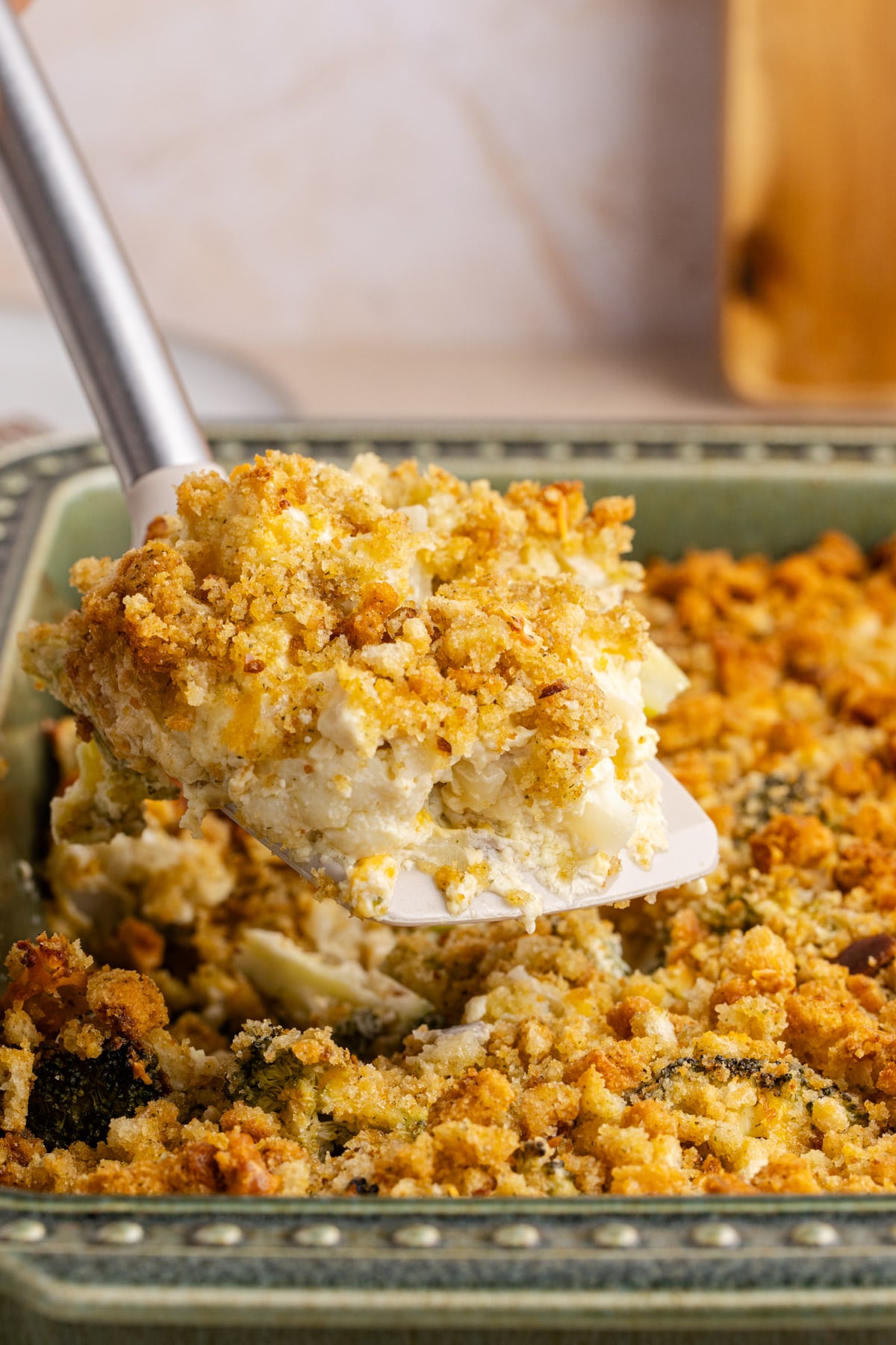 A spatula lifting up some casserole with broccoli and cauliflower.