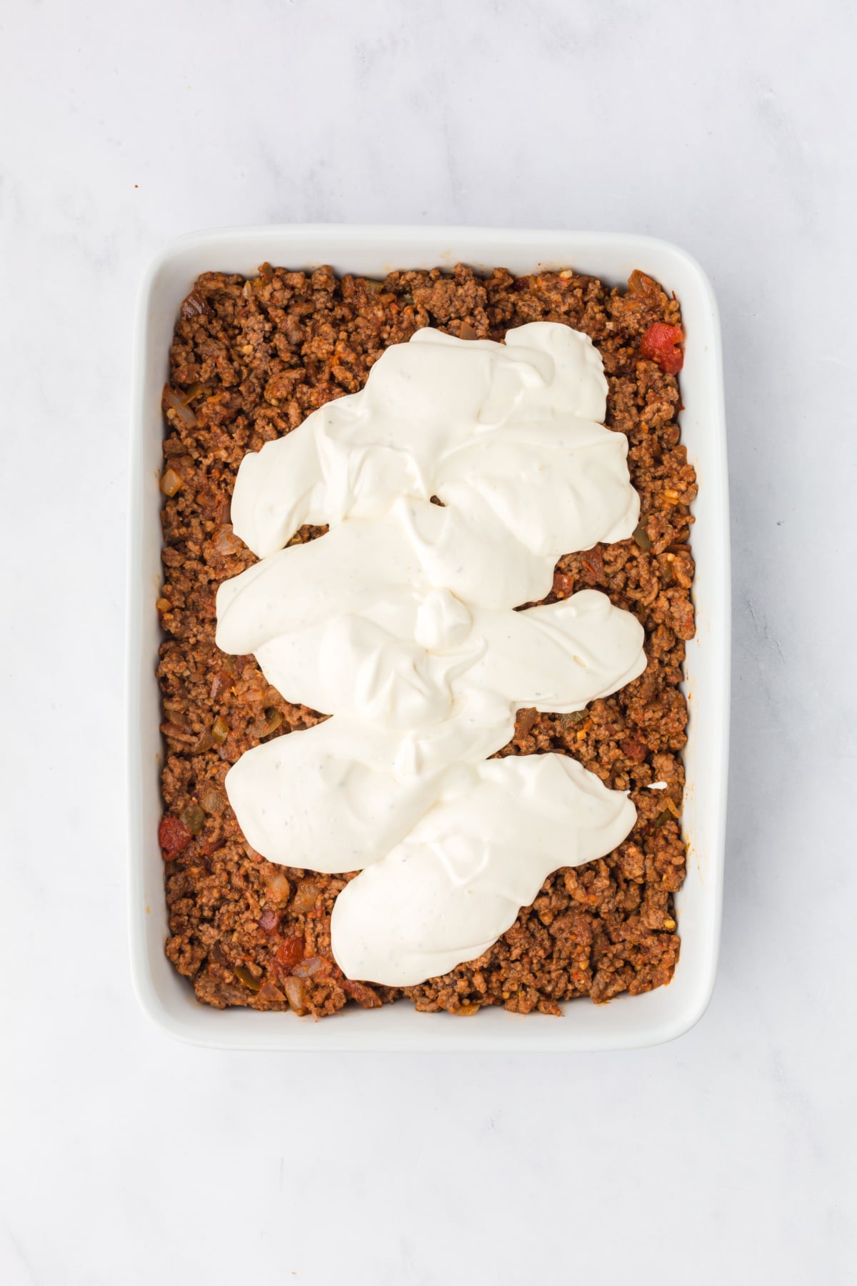 The beef mixture poured on top of the biscuit layer and then the mayonnaise and sour cream spread on top.