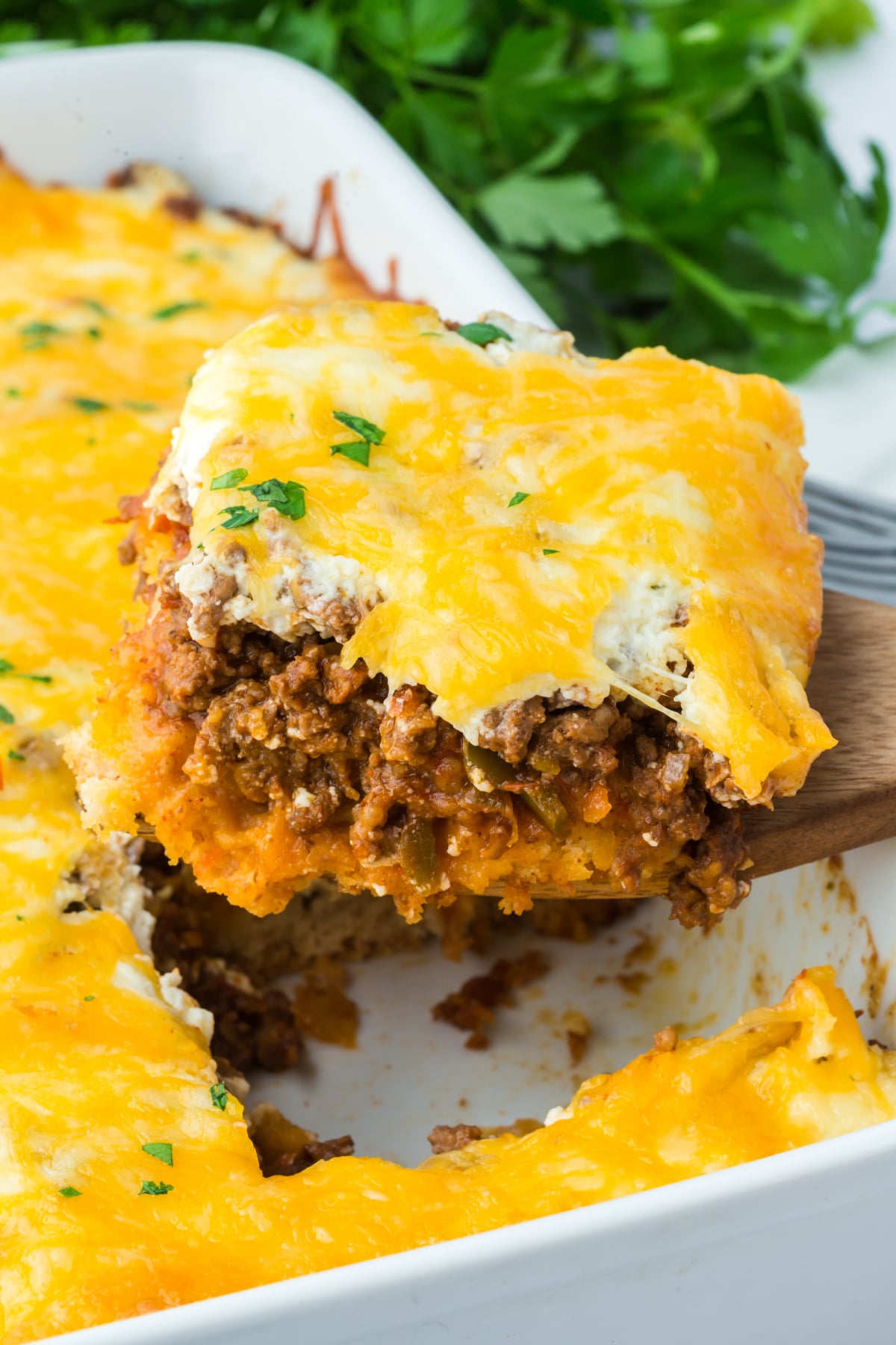 A slice of casserole being taken out of the baking dish.