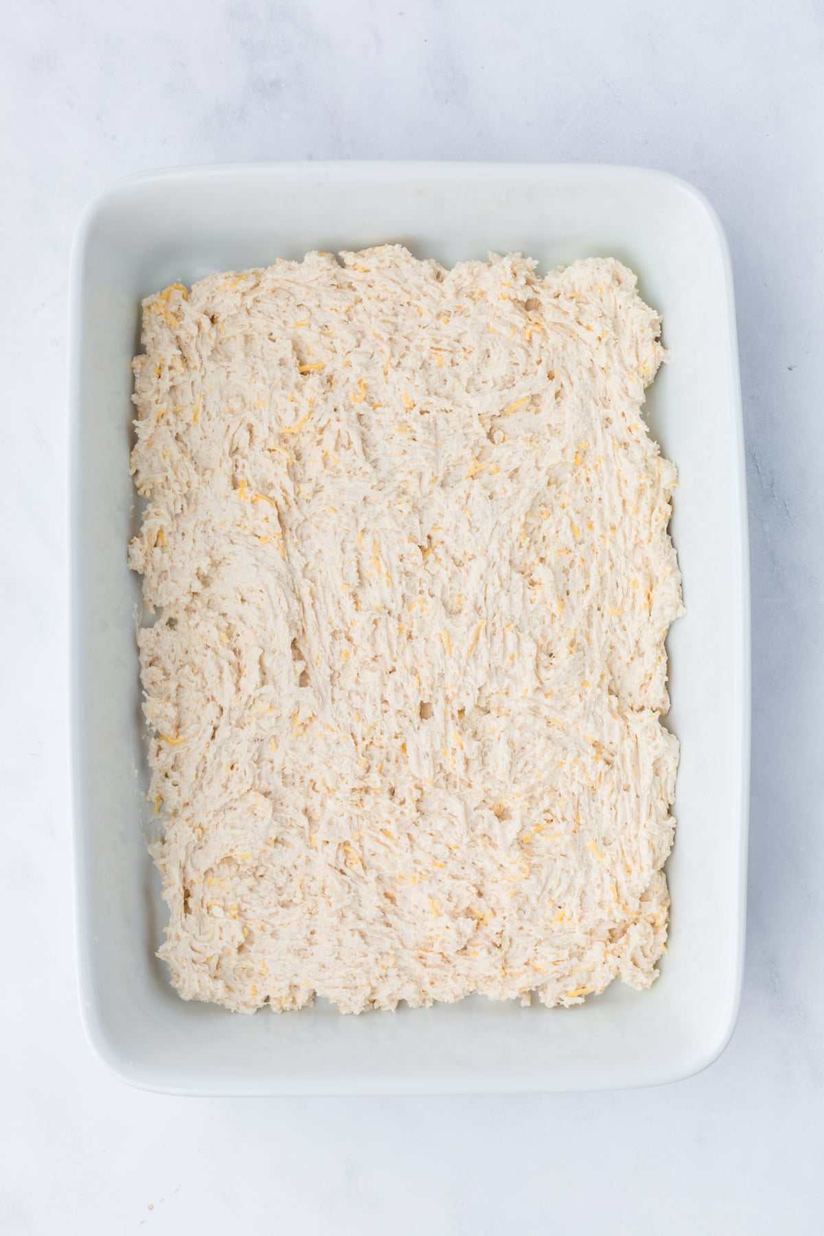The biscuit mix with water and shredded Colby Jack in a baking dish.