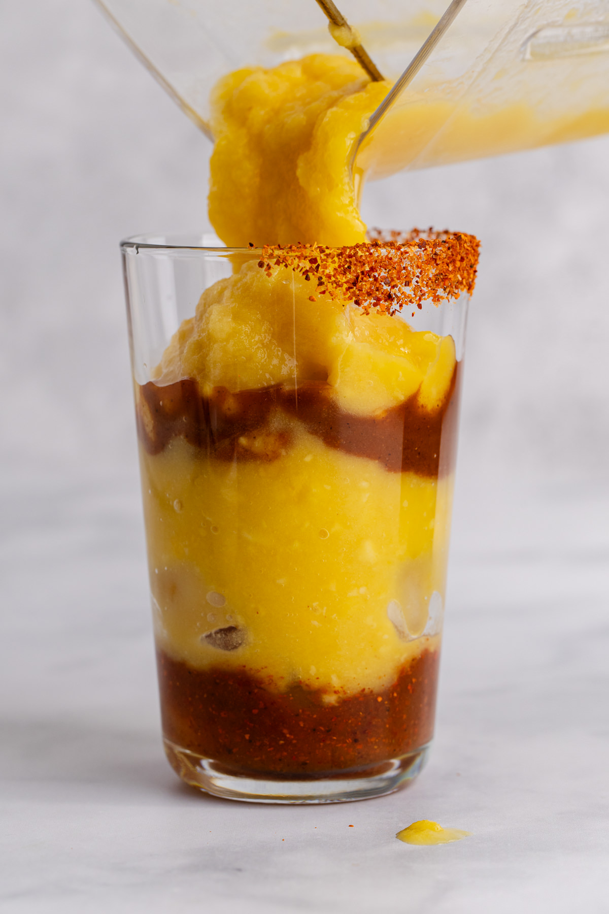 Lime juice, chamoy, and Tajin at the bottom of the glass and layered with the mango mixture.