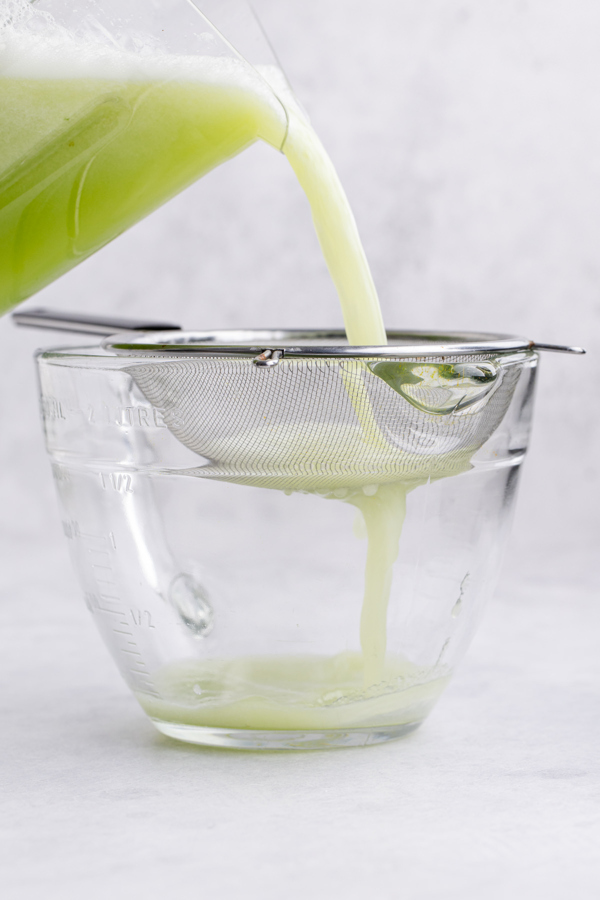 The cucumber and water being strained.