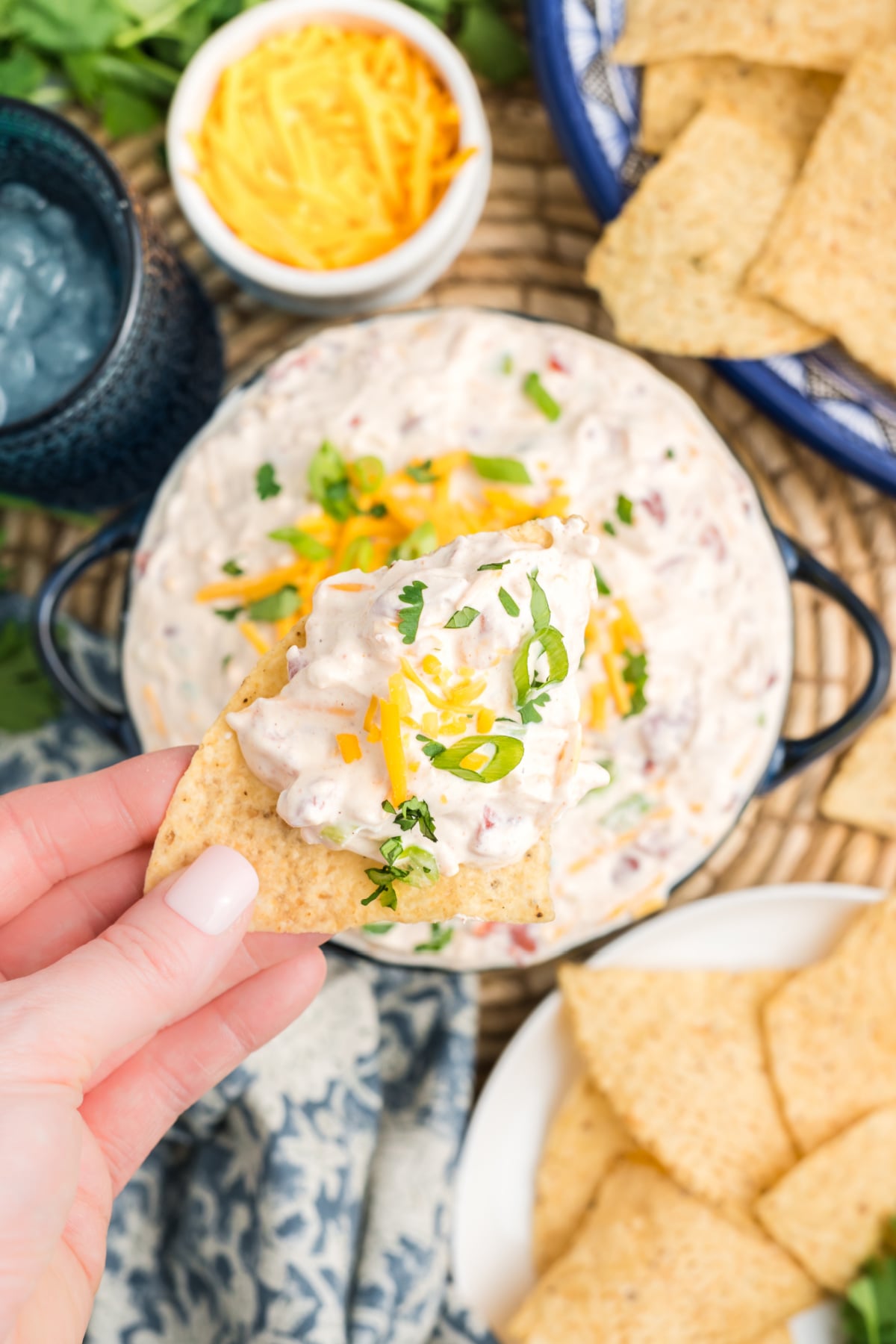 A hand holding a chip with taco dip in the air.