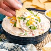 A chip scooping out some boat dip from a bowl.