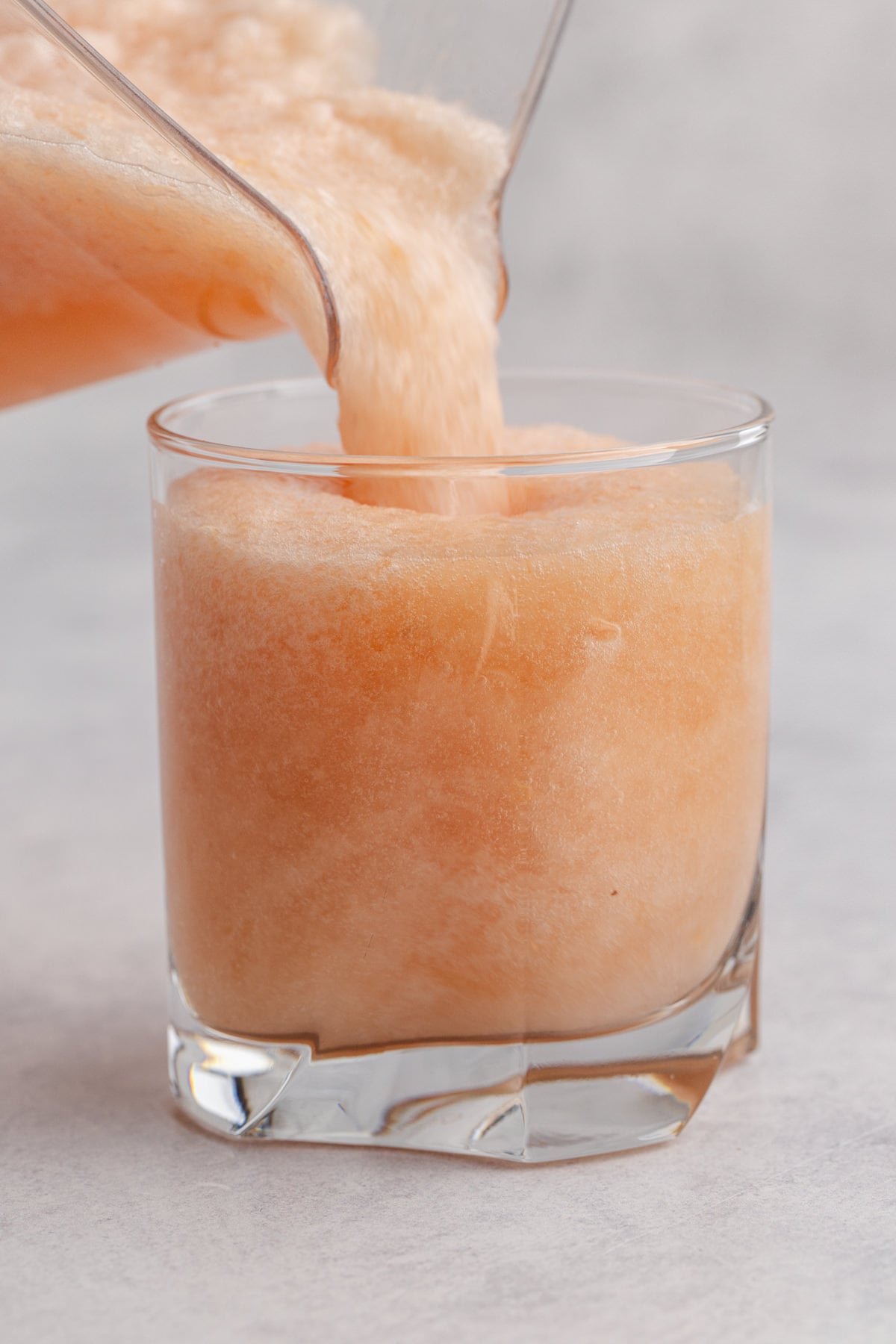 The blended drink being poured into the glass.