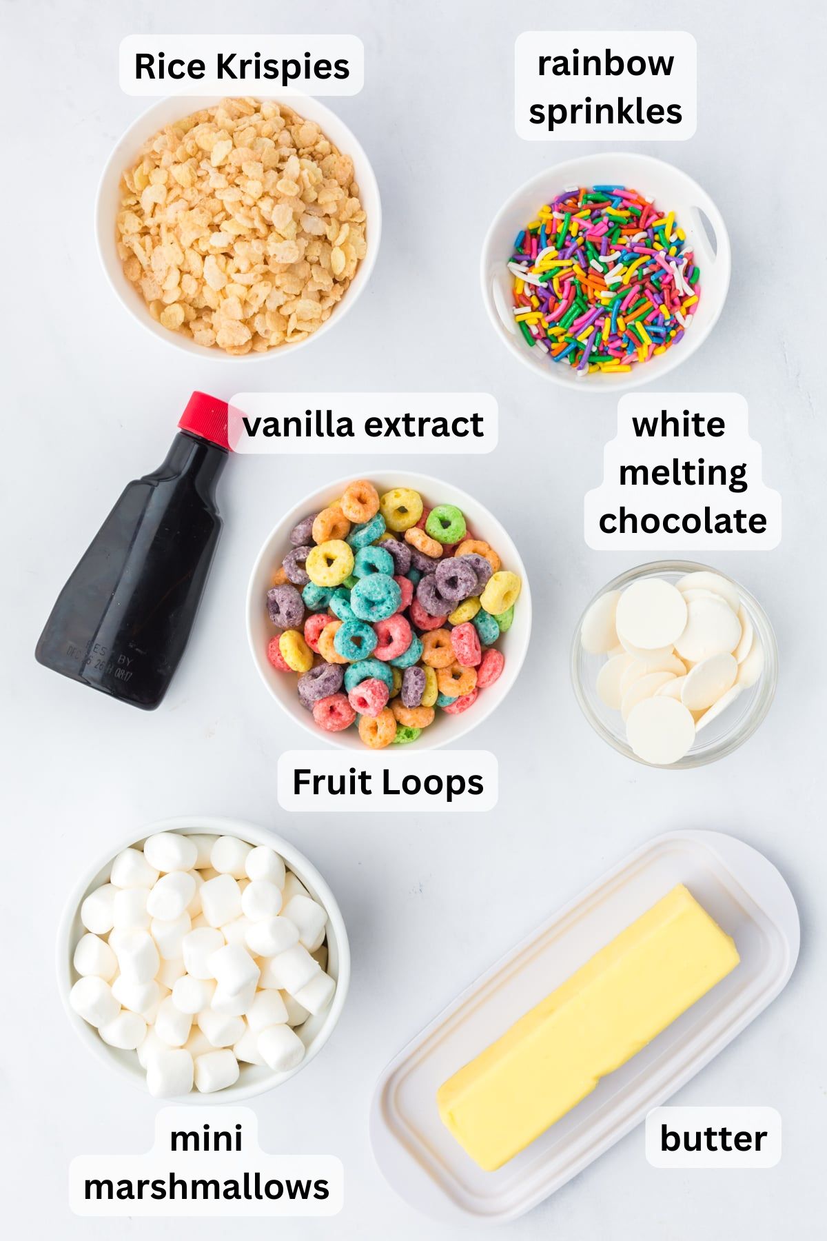 All of the Ingredients needed to make Fruit Loops Rice Krispies Treats in measuring tools and bowls on a table.
