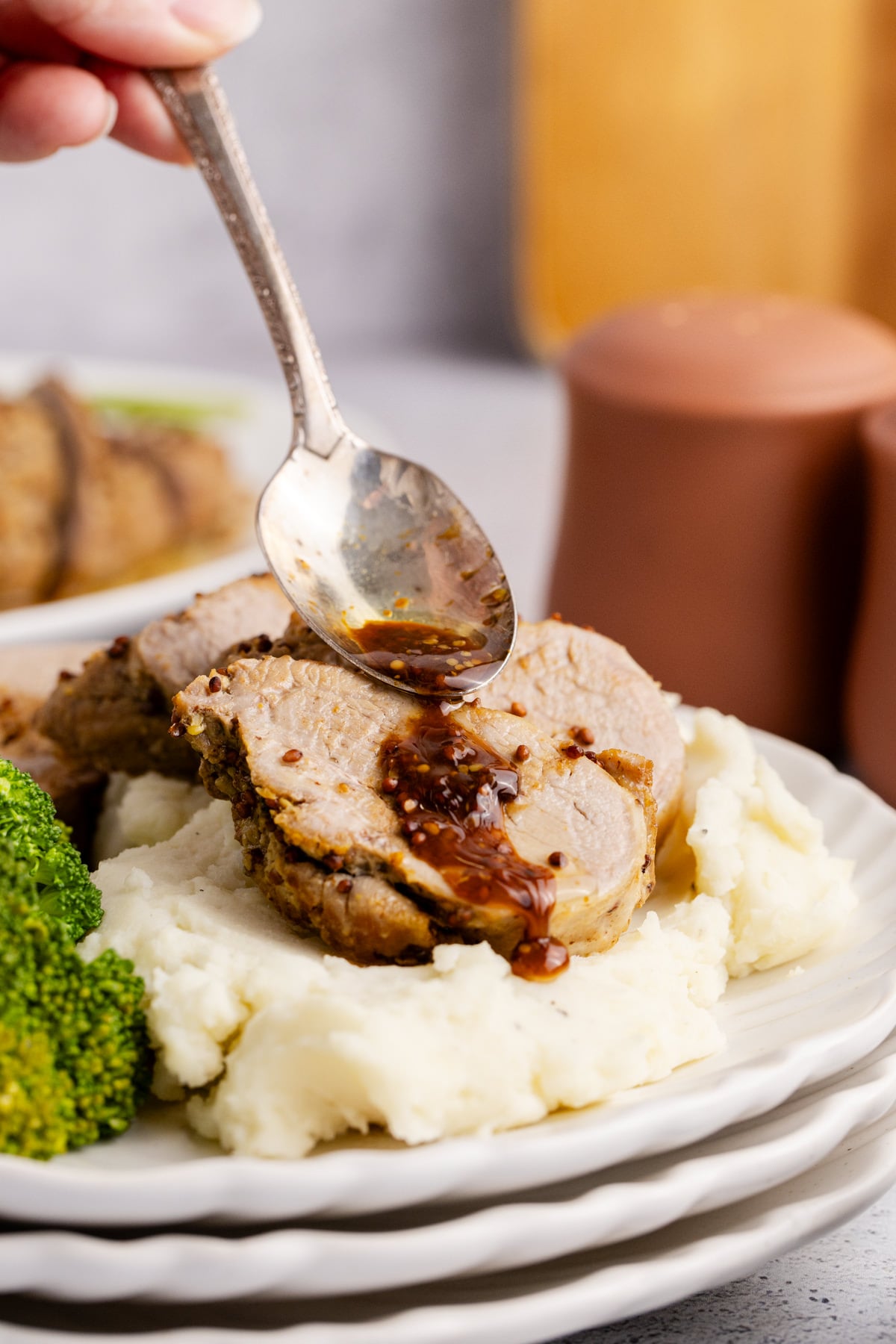 A spoon pouring glaze over the top of the pork tenderloin.