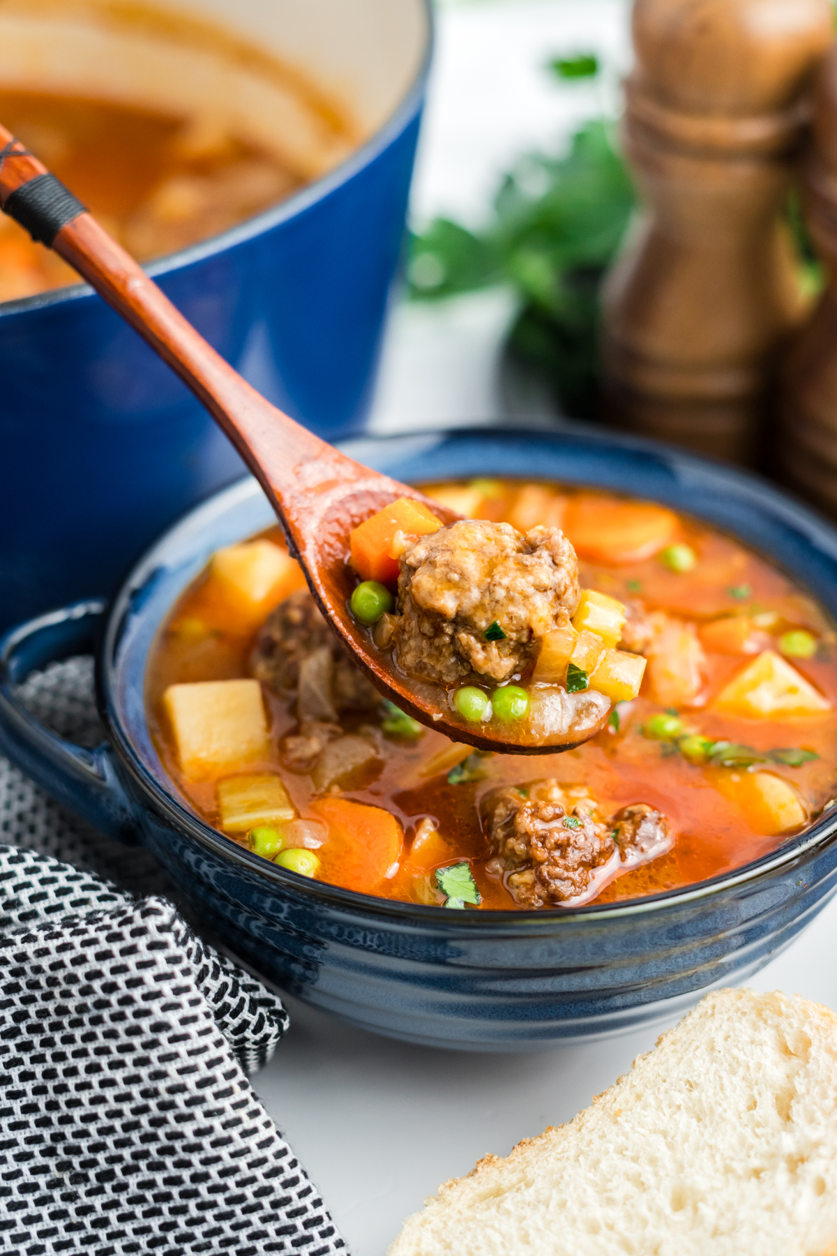 A wooden spoon scooping a meatball from the stew.