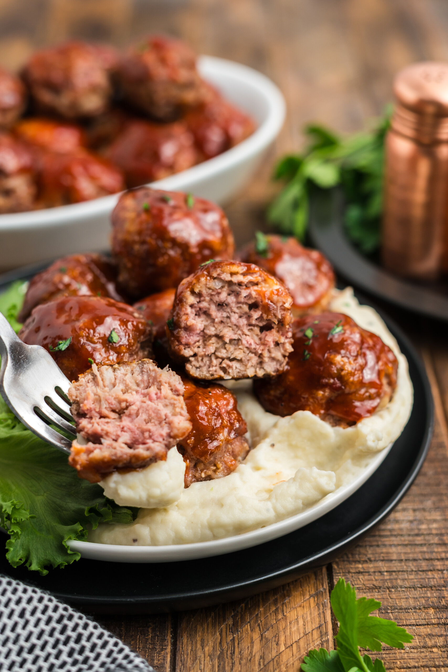 A fork filled with meatloaf meatballs and mashed potatoes.