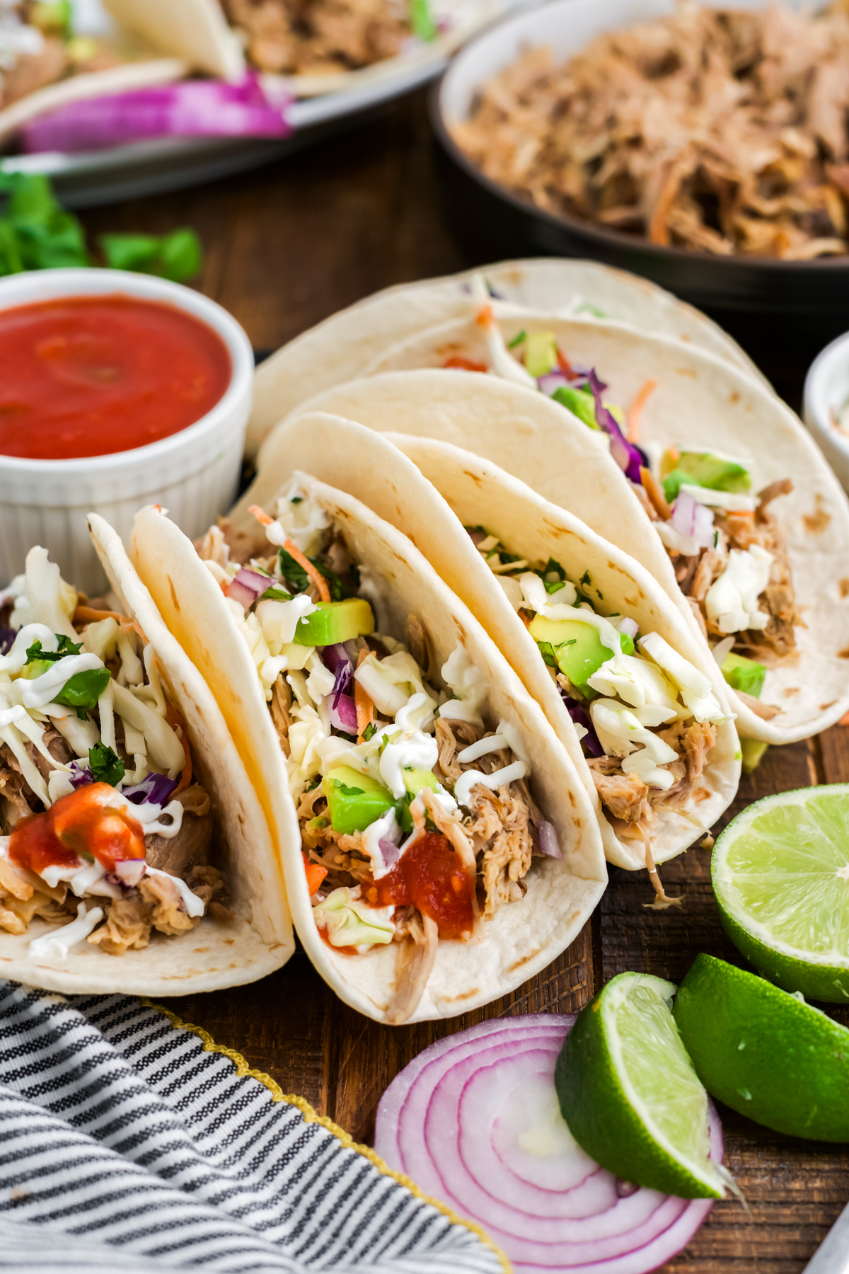 A row of pulled pork tacos on a platter with dip.