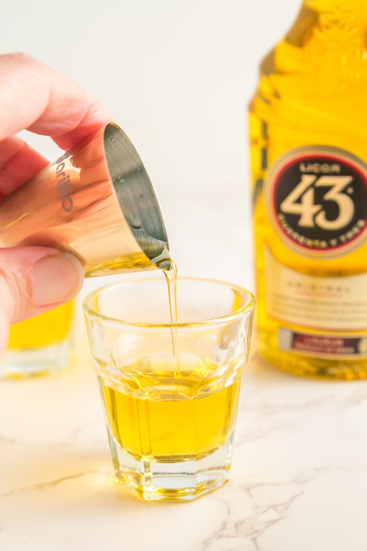 Licor 43 being added to the shot glass.