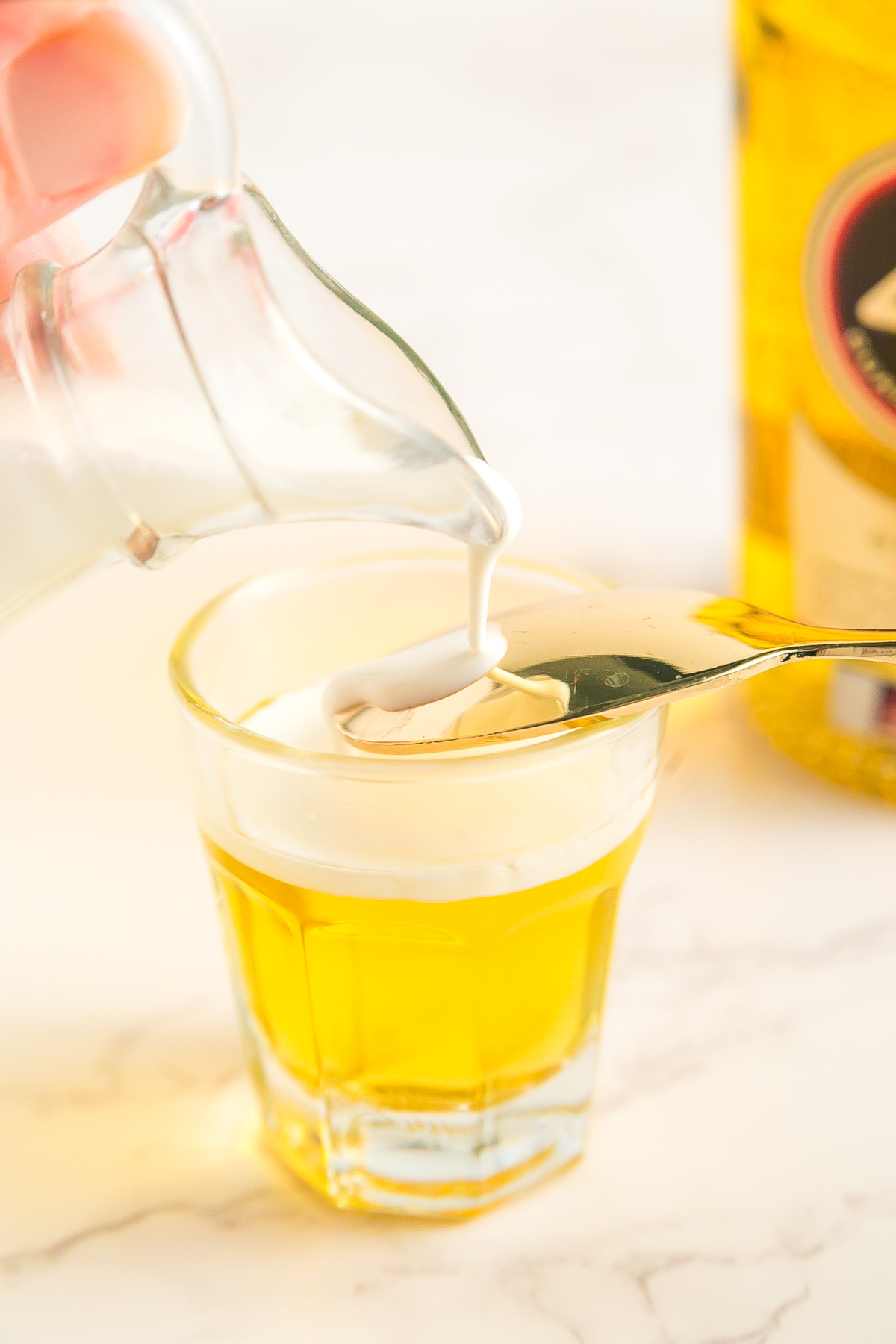 Heavy whipping cream being poured on the back of a spoon to create the top layer.
