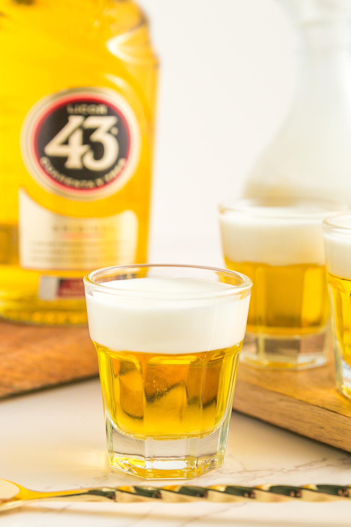 Mini beer shot on a table with a bottle and another shot.