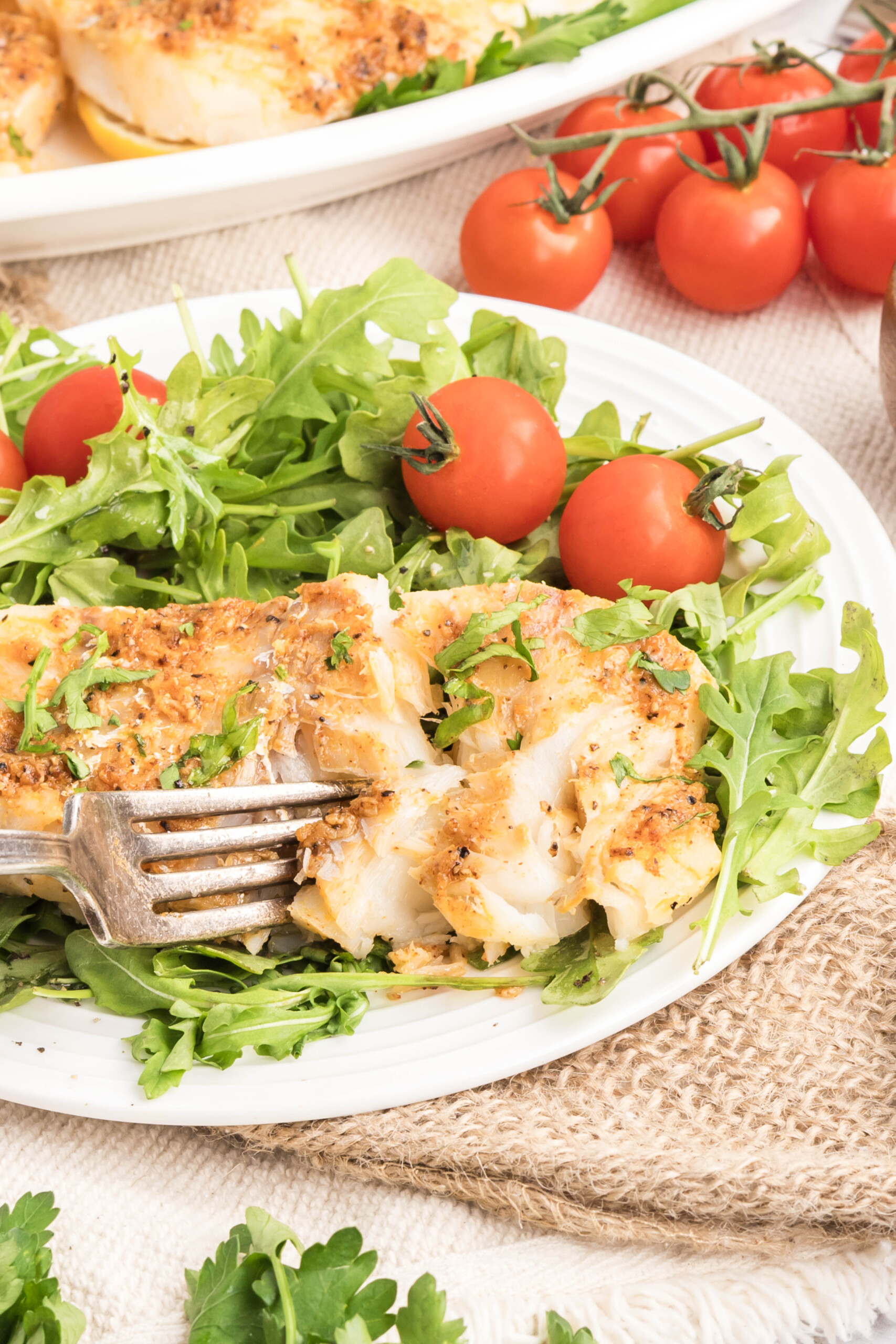 A fork picking up some fish from the plate.