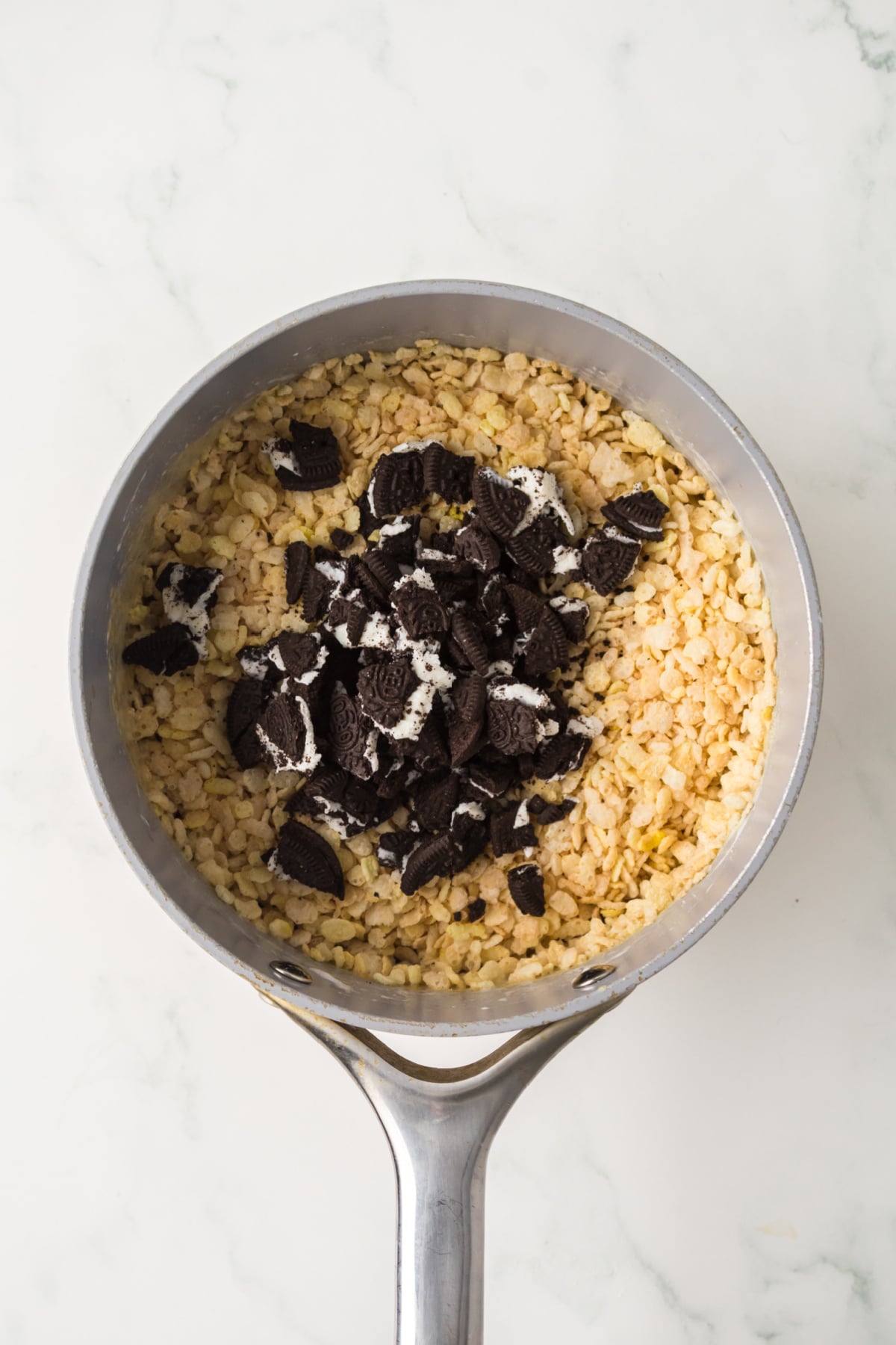 Rice Krispie mixture in pot with Oreo pieces added.