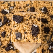 Peanut Butter Oreo Rice Krispie Treats in a pan with one held in the air above them on a spatula.