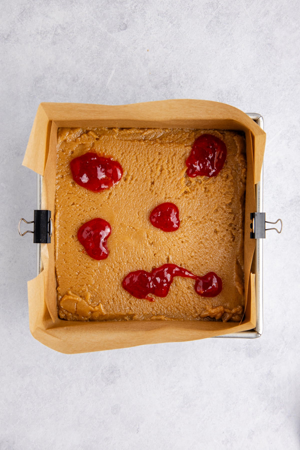 Strawberry jam dolloped on top of the peanut butter dough.