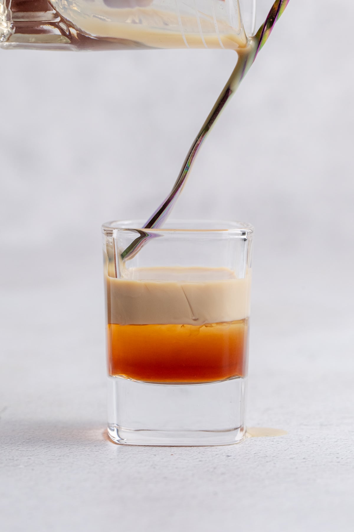 The same spoon is hovering over the Frangelico while the Bailey's layer is slowly added.