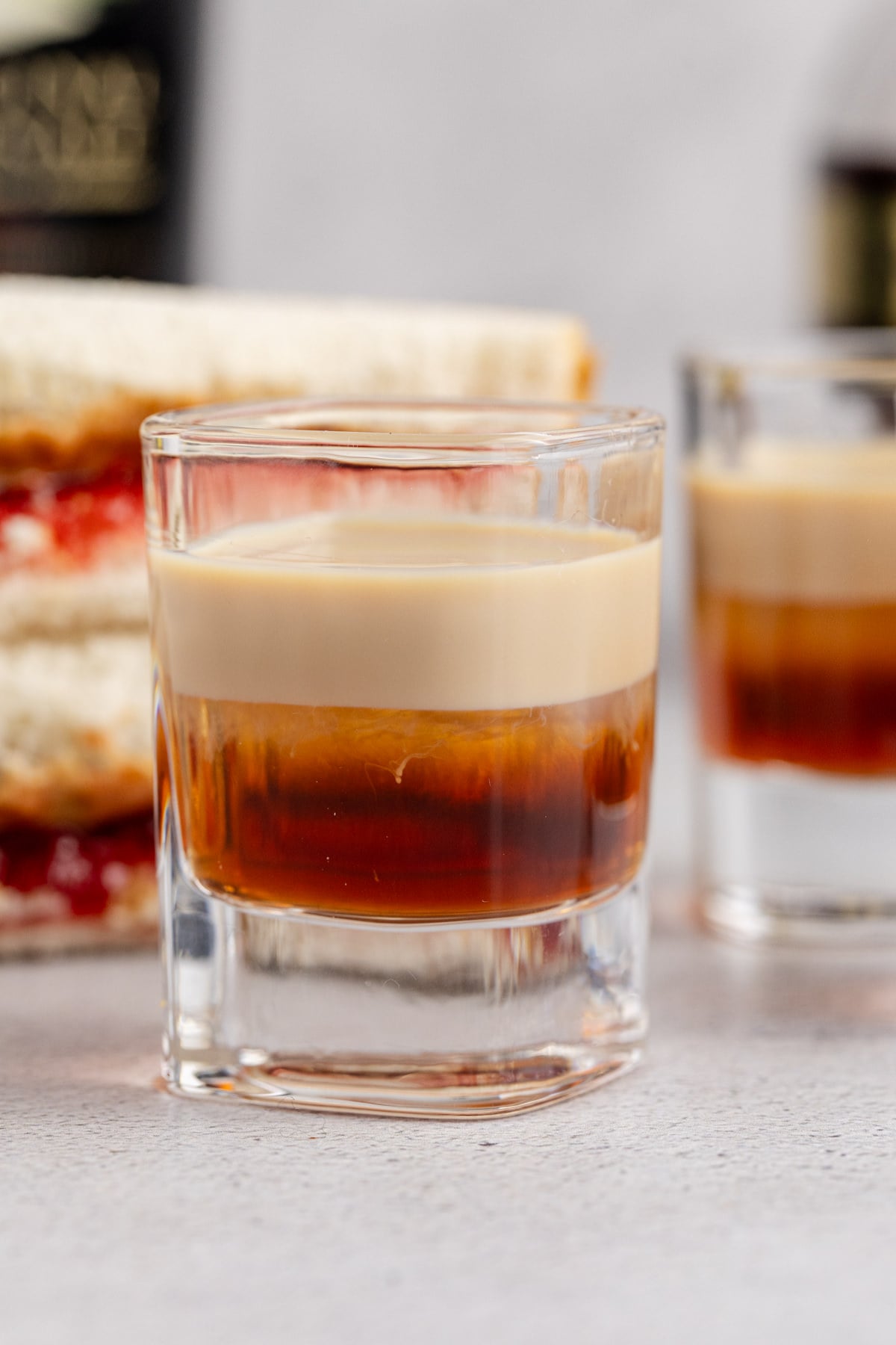 A couple Peanut Butter and Jelly Shots on a table wiyth a peanut butter and jelly sandwich.
