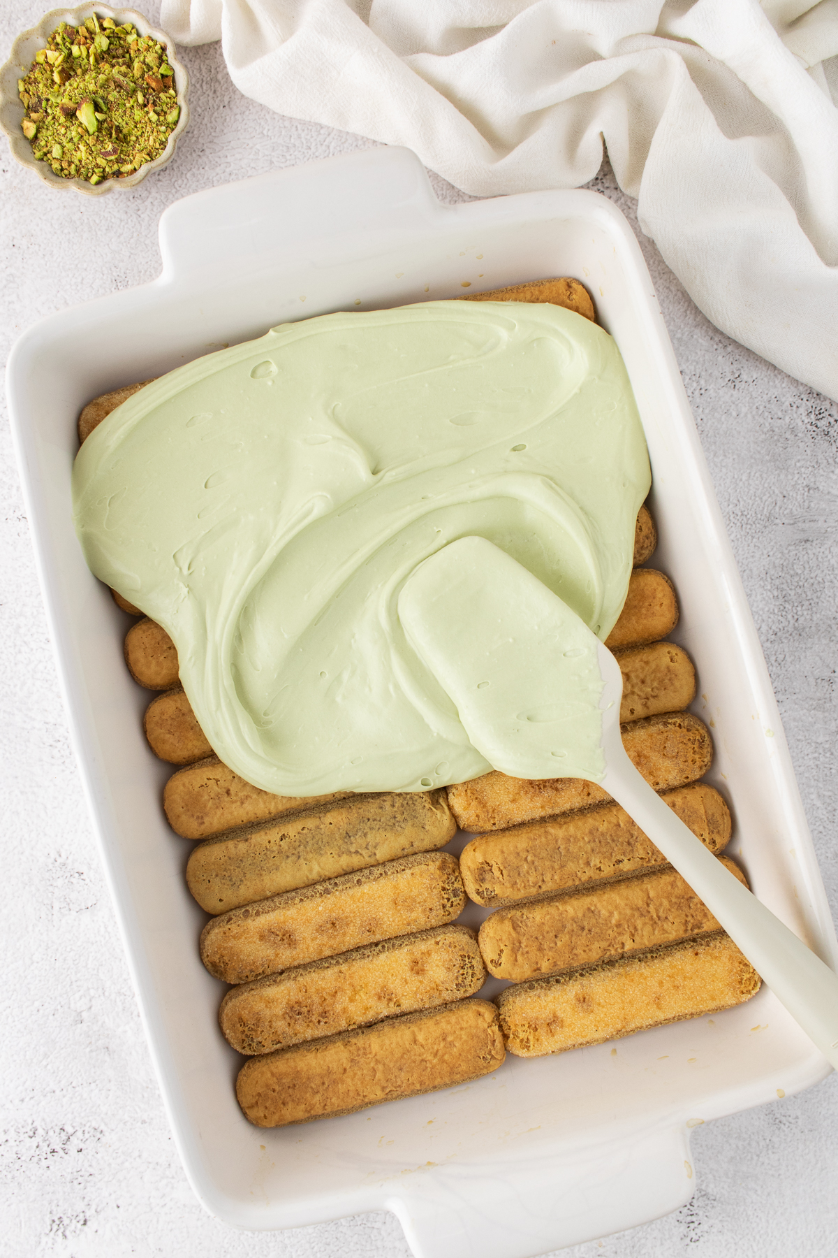 Half of the cream mixture is added on top of the lady fingers.