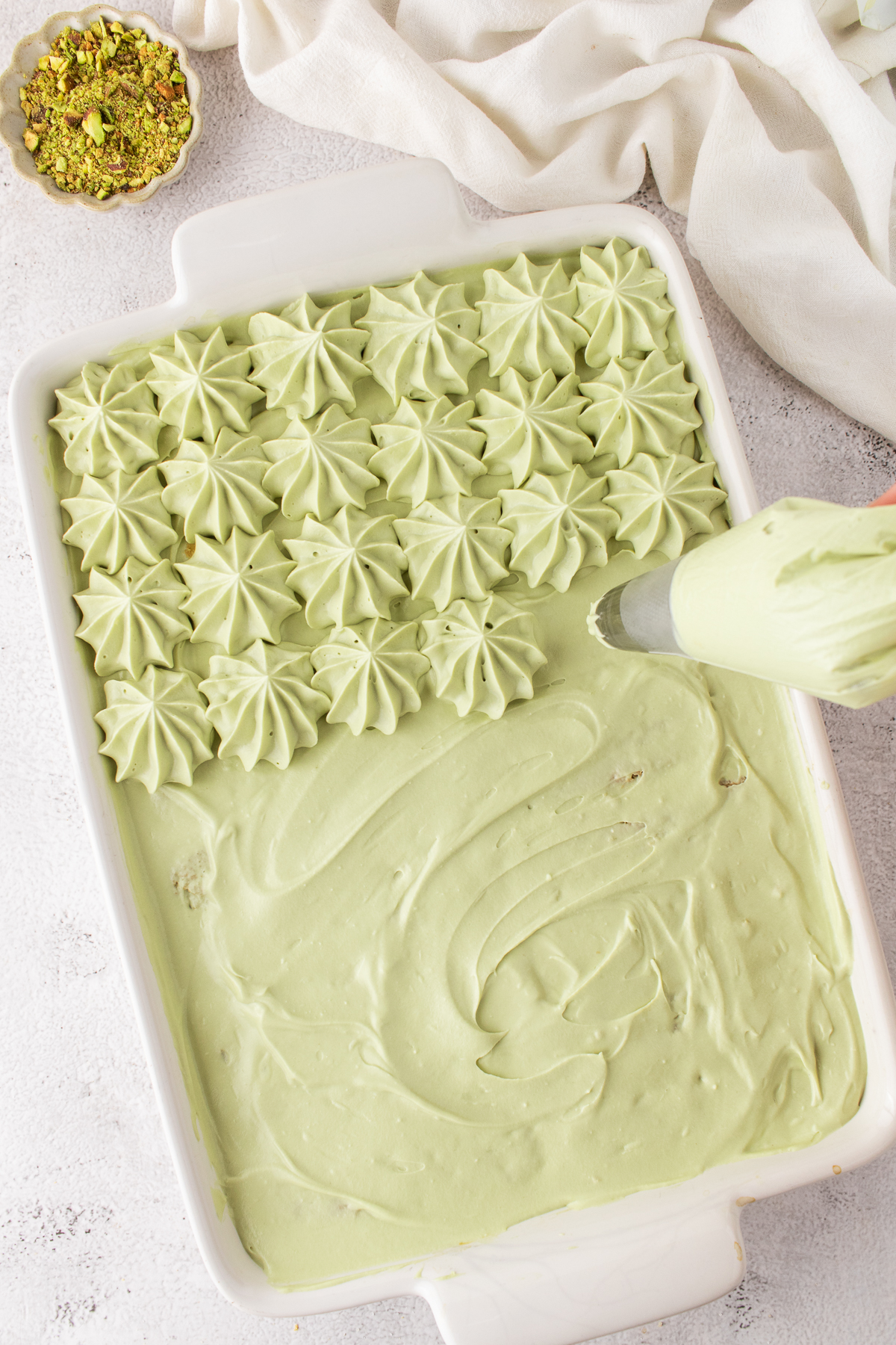 Cream mixture covers lady fingers and remainig is piped on top in a pattern.