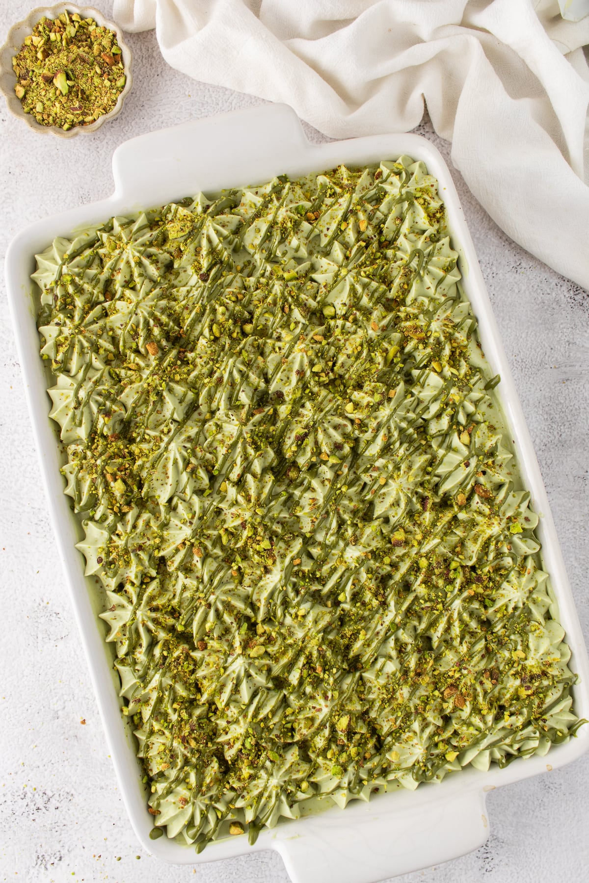 Drizzle is added to finished pistachio tiramisu with a sprinkling of finely chopped pistachios.