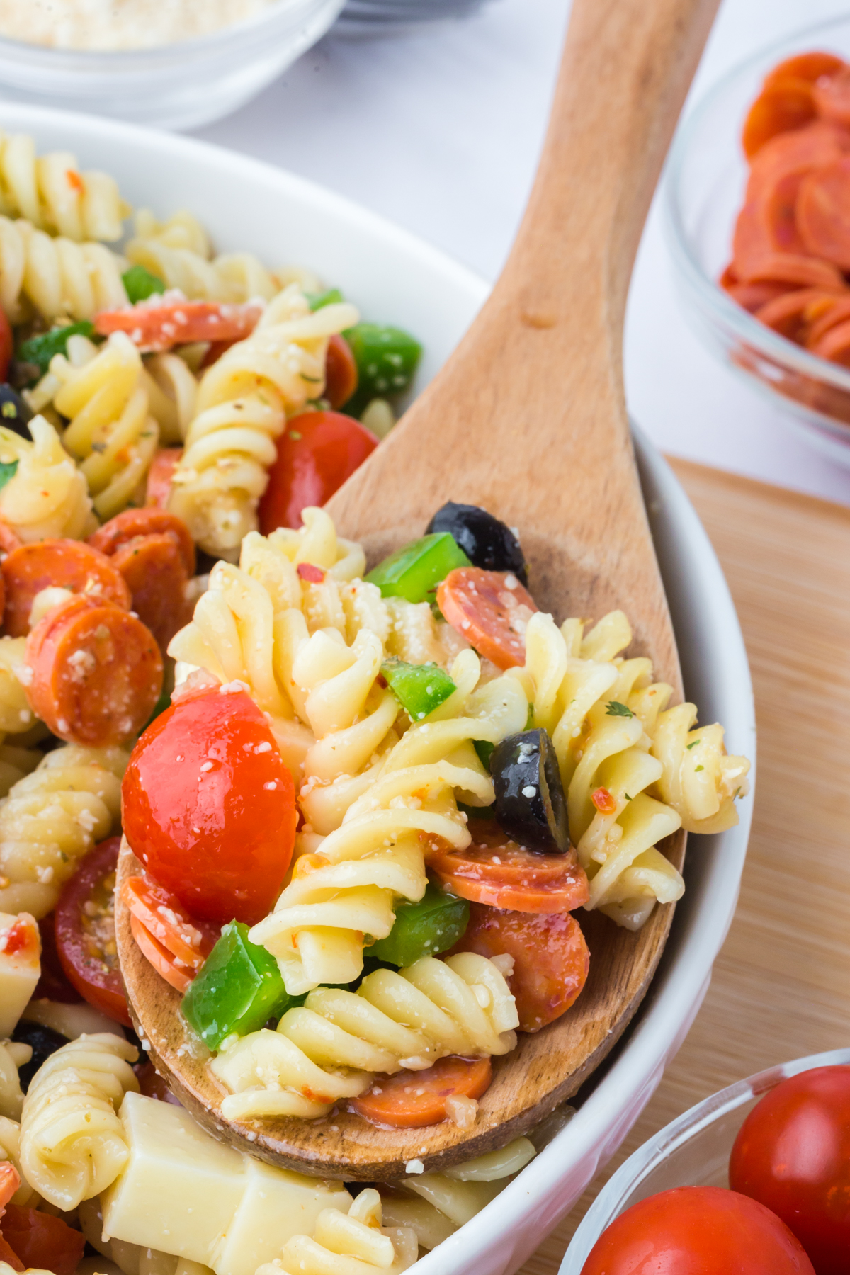 A bowl of salad with a wooden spoonful being lifted out of the bowl.