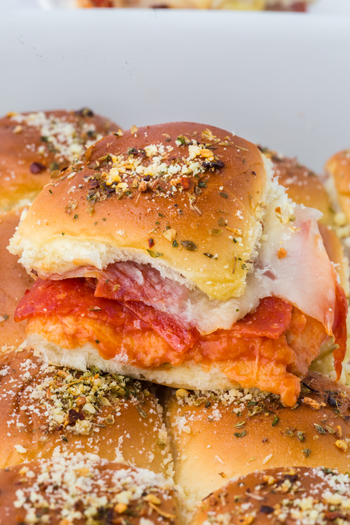 A pan full of Pizza Sliders with one on top.